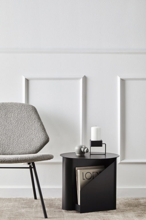 Detailaufnahme eines Wohnzimmers mit Woud Teppich, Stuhl und Beistelltisch in minimalistischem Design.
