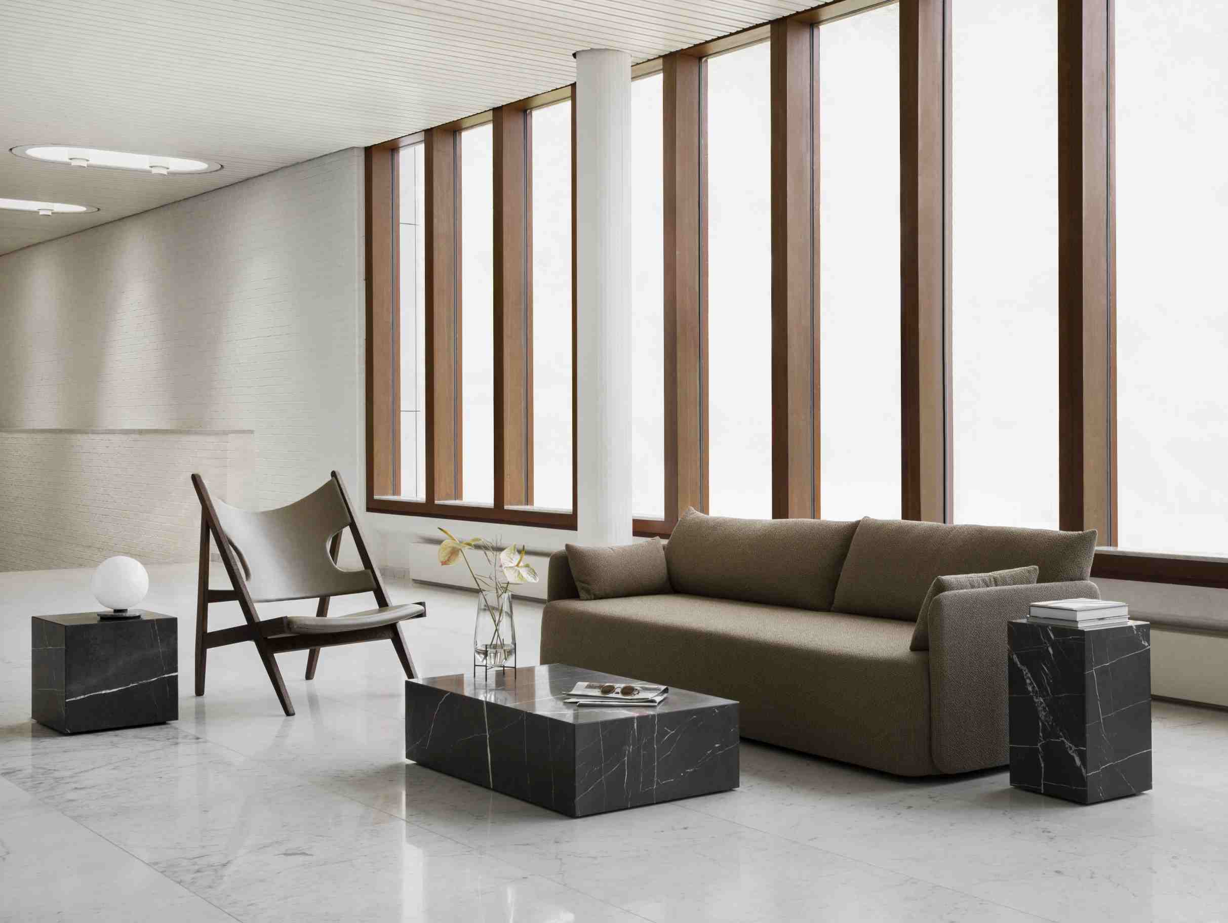 Audo Plinth Cubic Beistelltisch aus Marmor in modernem Wohnzimmer mit Sofa und Sessel.
