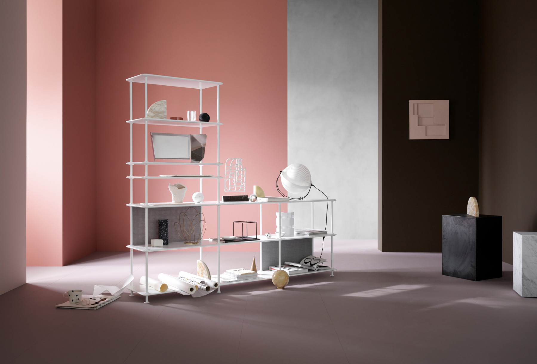 Weißes modulares Regal mit Deko-Objekten vor rosa und braunem Hintergrund, modernes Wohnzimmer Möbel.