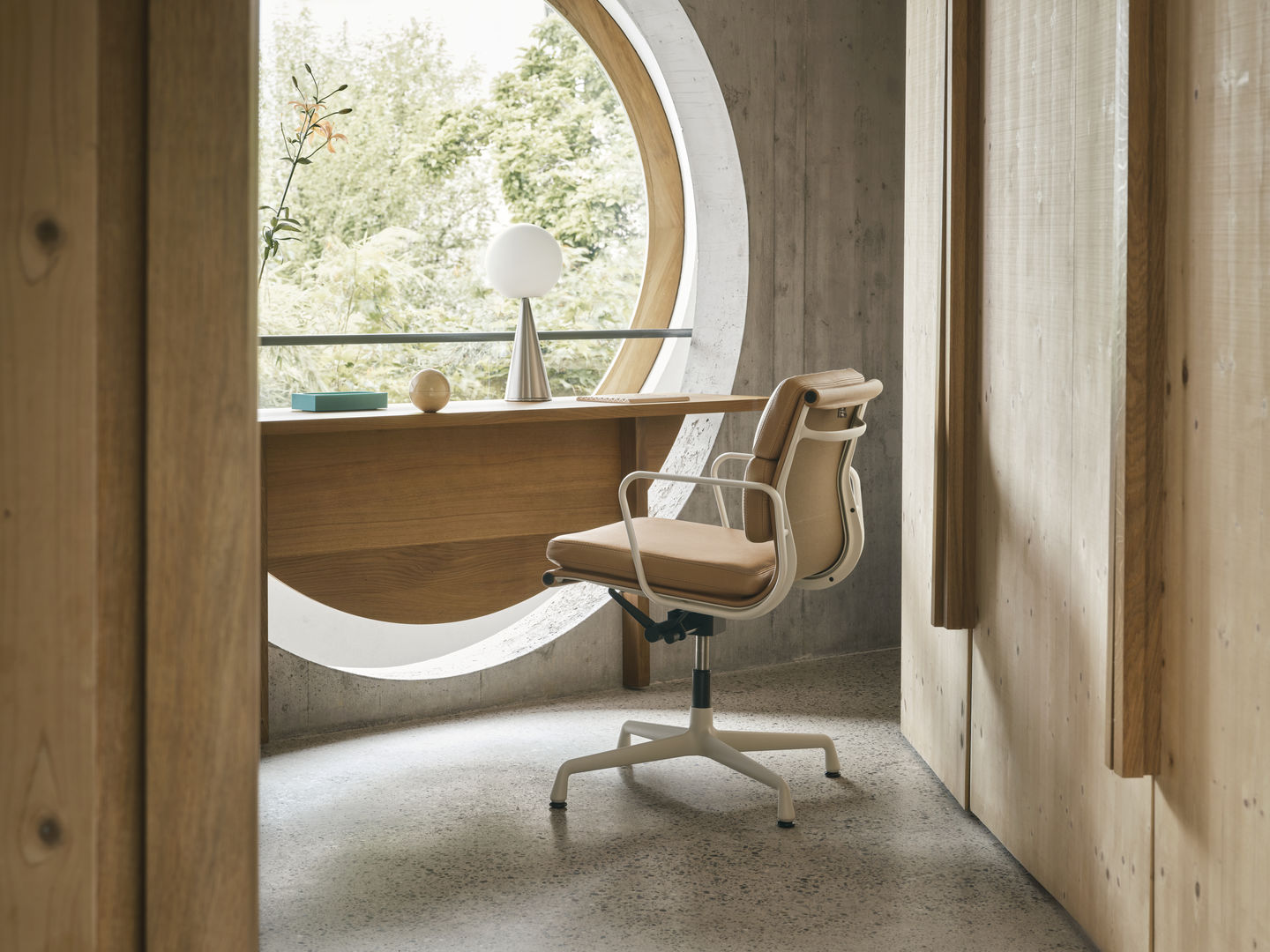 Vitra EA 231 Soft Pad Chair in Beige vor einem runden Fenster und Holzwand.