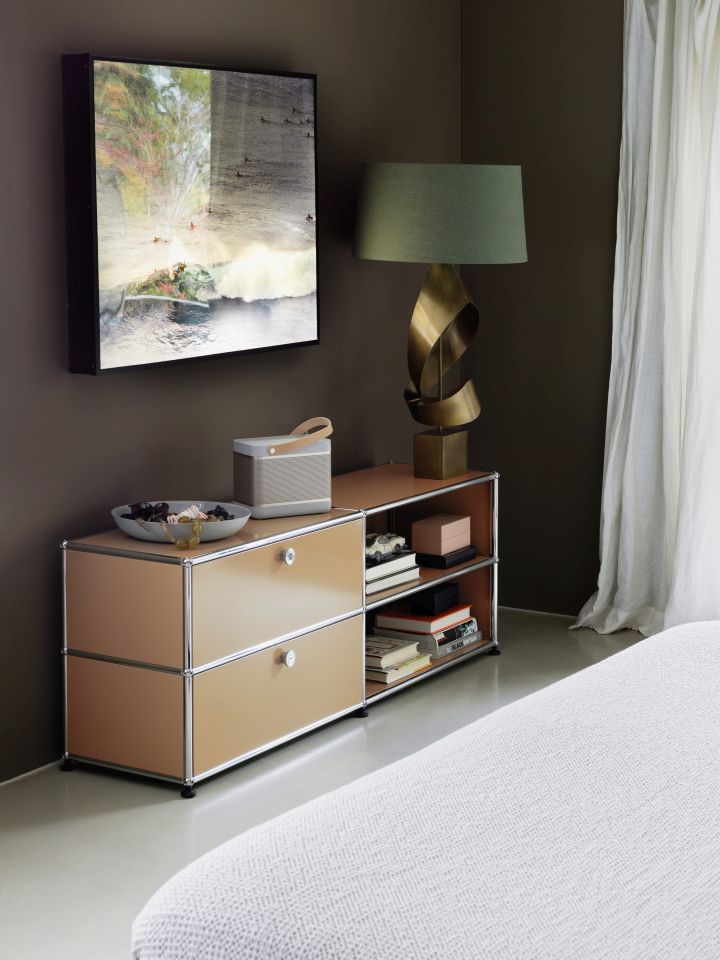 Beige Kommode mit Schubladen und offenen Regalen, dekoriert mit Lampe, Lautsprecher und Kunstwerk.