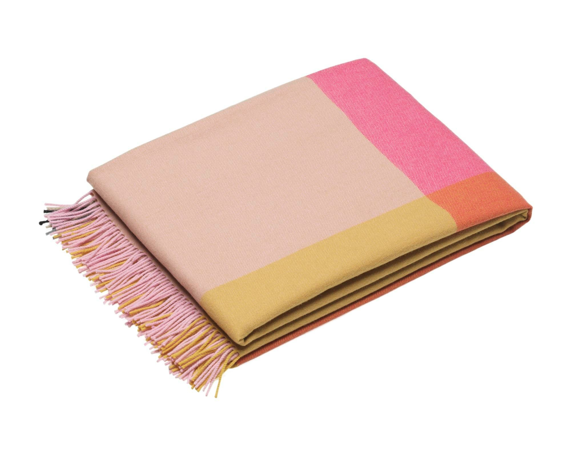 Gefaltete Vitra Wolldecke im Colour Block Design mit Fransen in Rosa, Gelb und Orange.