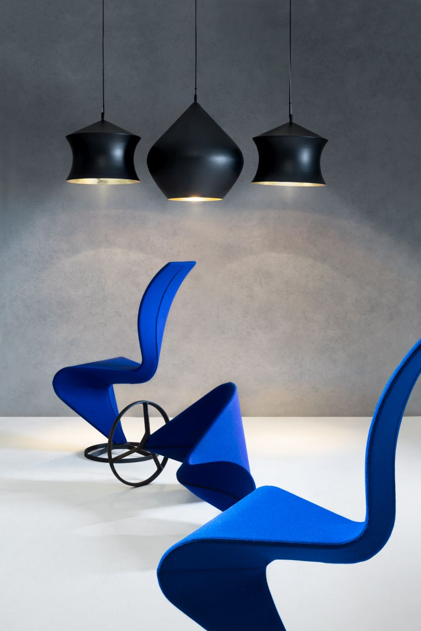 Drei schwarze Tom Dixon Beat Waist Pendelleuchten über blauen Designstühlen, moderne Innenraumbeleuchtung.