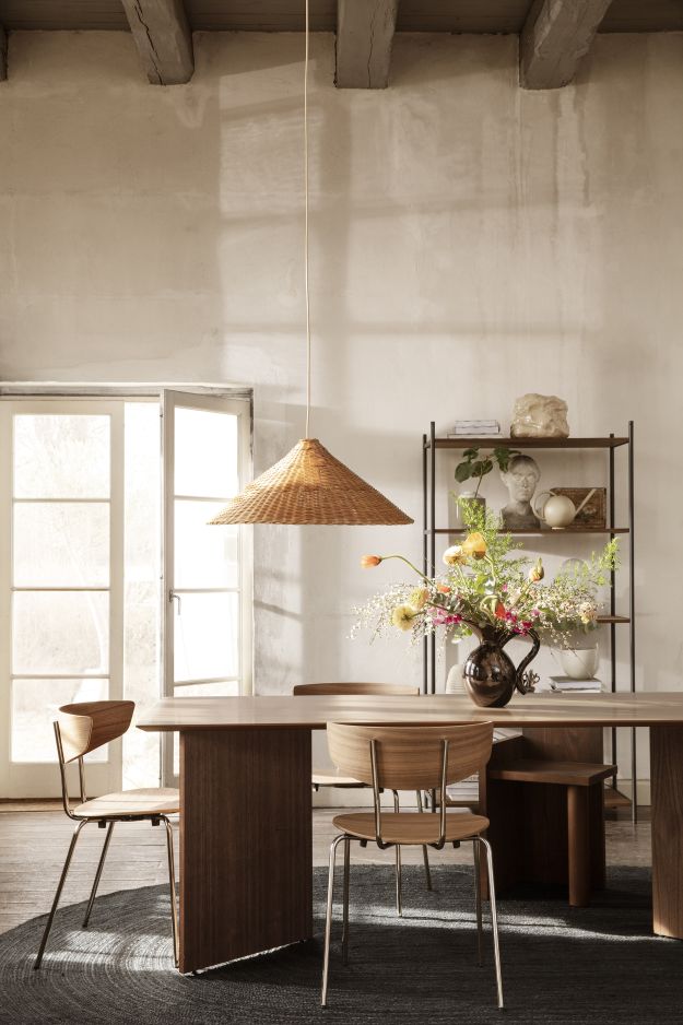 Esszimmer mit Ferm Living Mingle Table, Holzstühlen und Rattan-Lampe über einem dunklen Teppich.