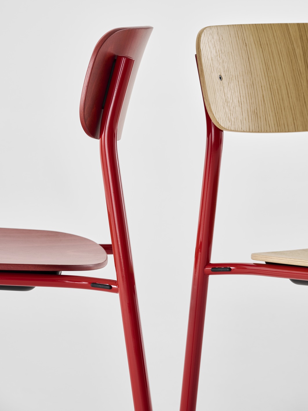Detailaufnahme von zwei S 243 Stahlrohrstühlen von Thonet, einer rot gebeizt, einer naturfarben, minimalistisches Design.