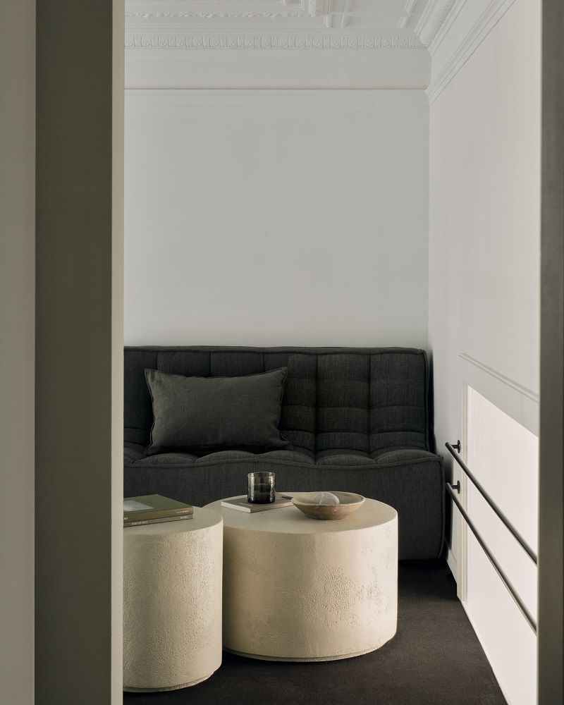 Ethnicraft Elements Couchtisch Microcement Off White Rund vor dunklem Sofa, minimalistisches Wohnzimmer Design.