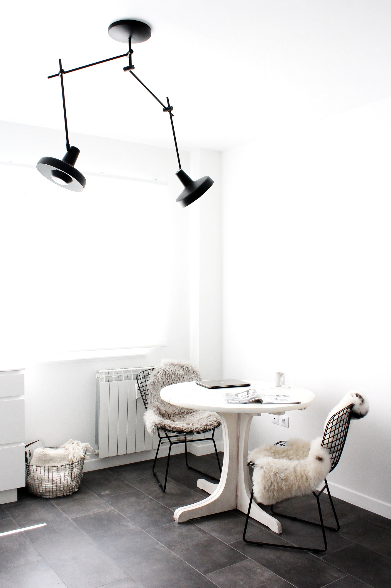 Esszimmer mit Arigato Deckenleuchte, schwarze Pendelleuchte über weißem Tisch und Stühlen mit Fell.