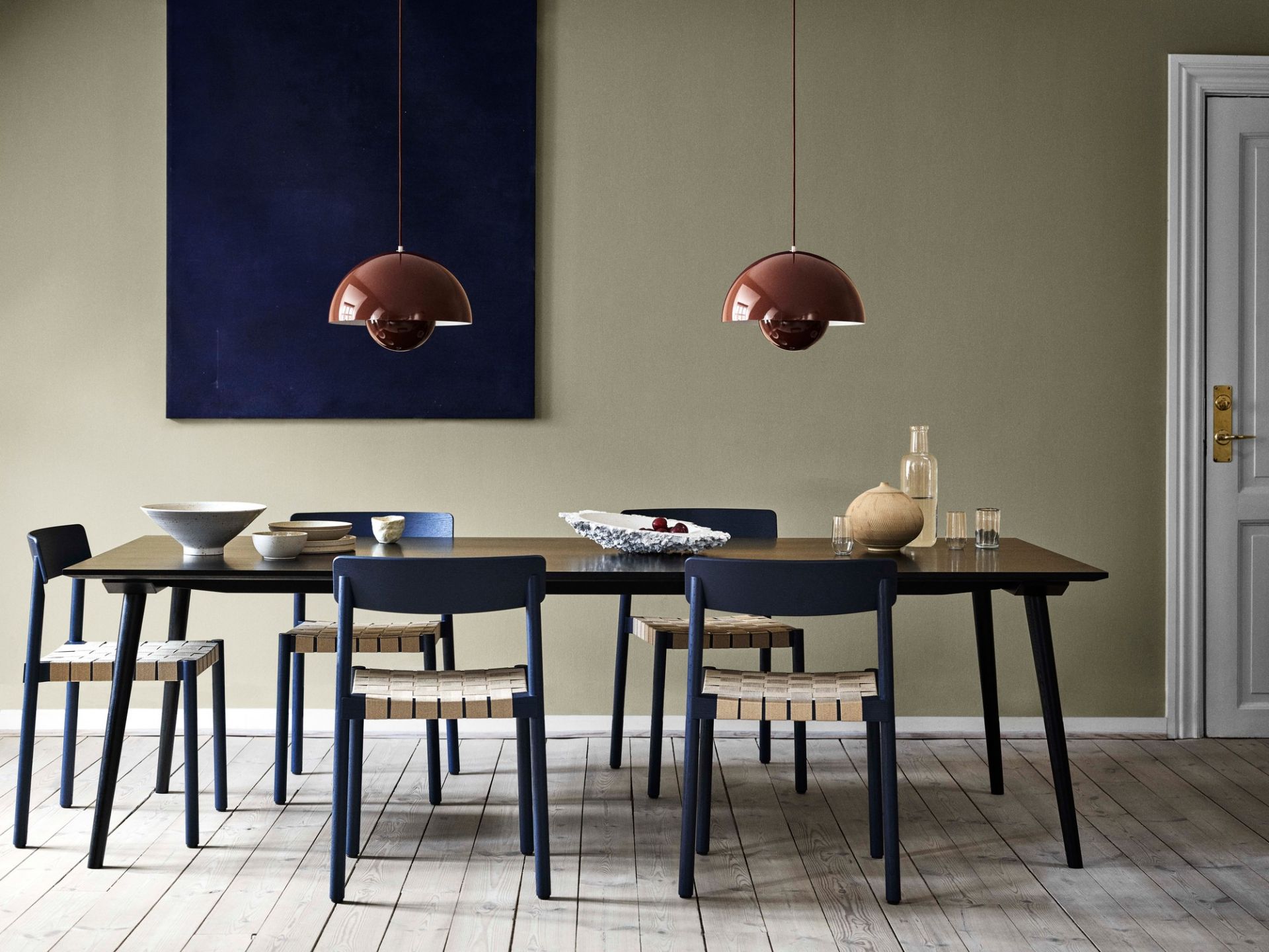 Esszimmer mit dunklem Holztisch, blauen Stühlen mit Webmuster und zwei braunen Pendelleuchten.