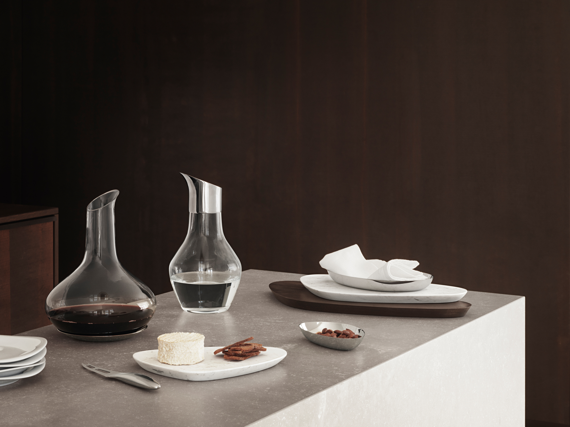 Sky Weinkaraffe von Georg Jensen mit Untersetzer, gefüllt mit Rotwein und Wasser, auf Tisch.