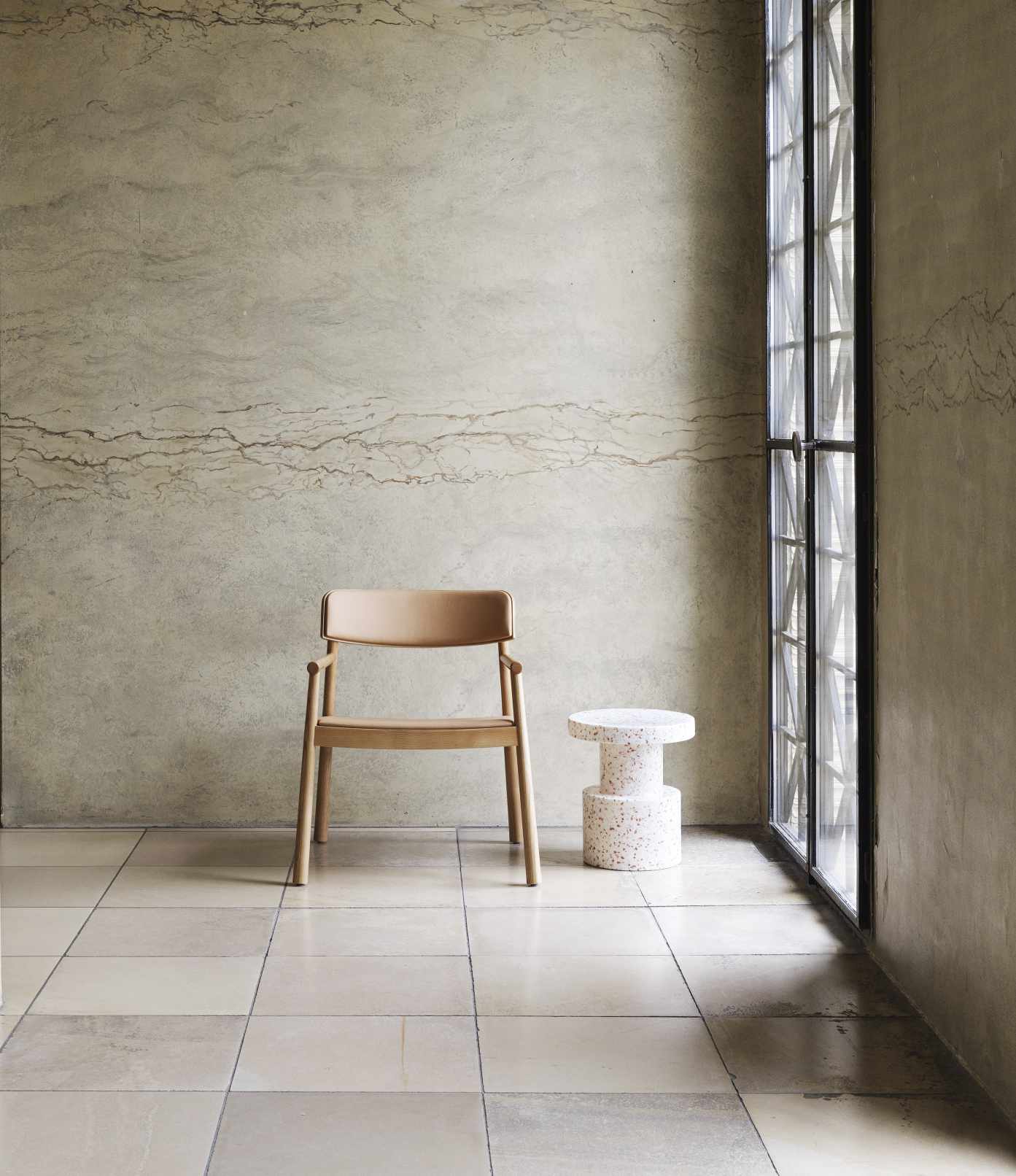 Normann Copenhagen Bit Stool Hocker in Weiß mit Terrazzo-Muster neben einem Fenster und Stuhl.