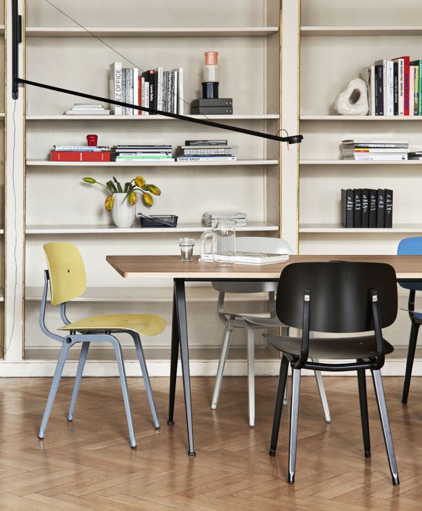 Gelber Revolt Chair Stuhl von Hay am Esstisch vor Bücherregal, modernes skandinavisches Design.
