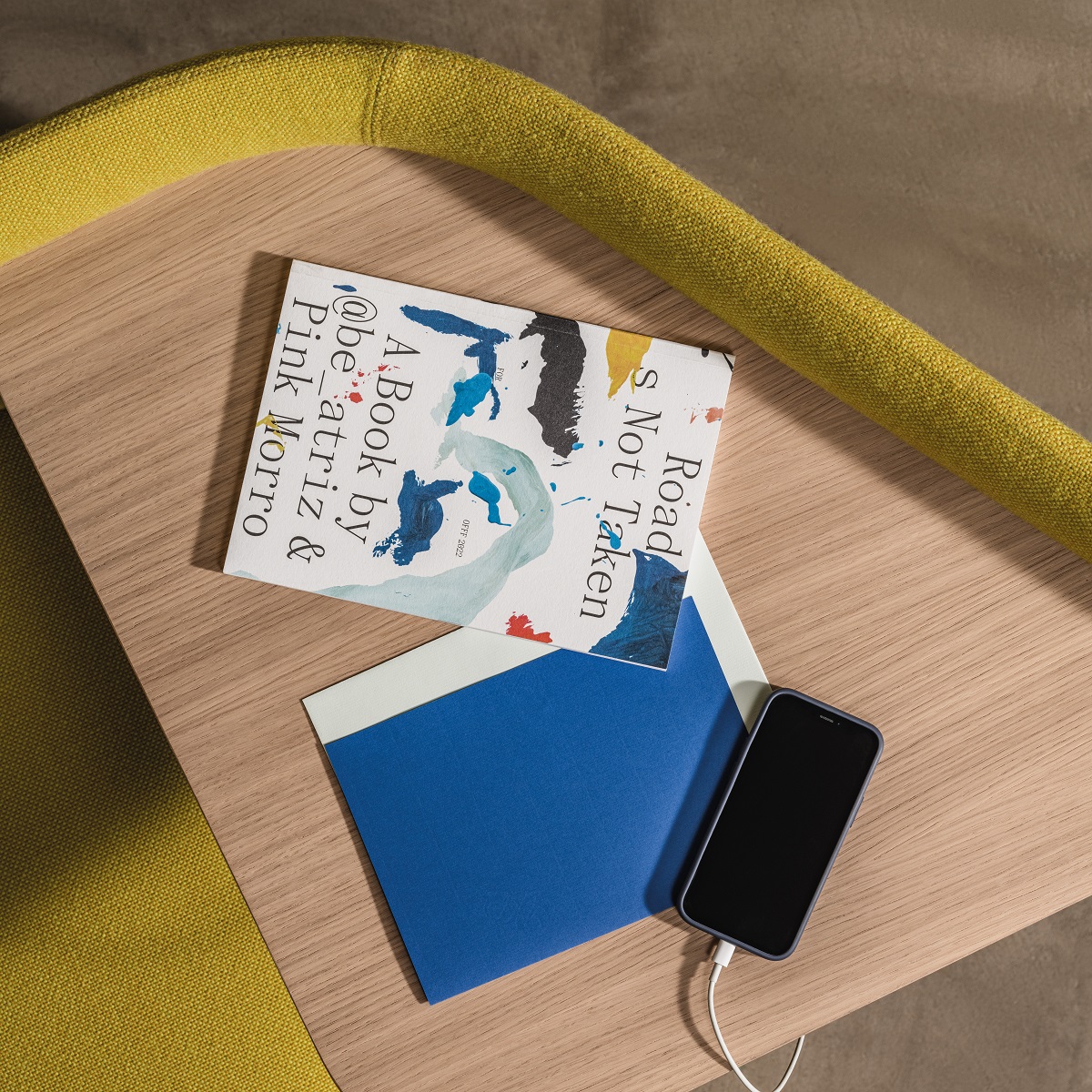 Detailaufnahme eines In Out Office Beistelltisches mit Buch, Notizbuch und Smartphone.