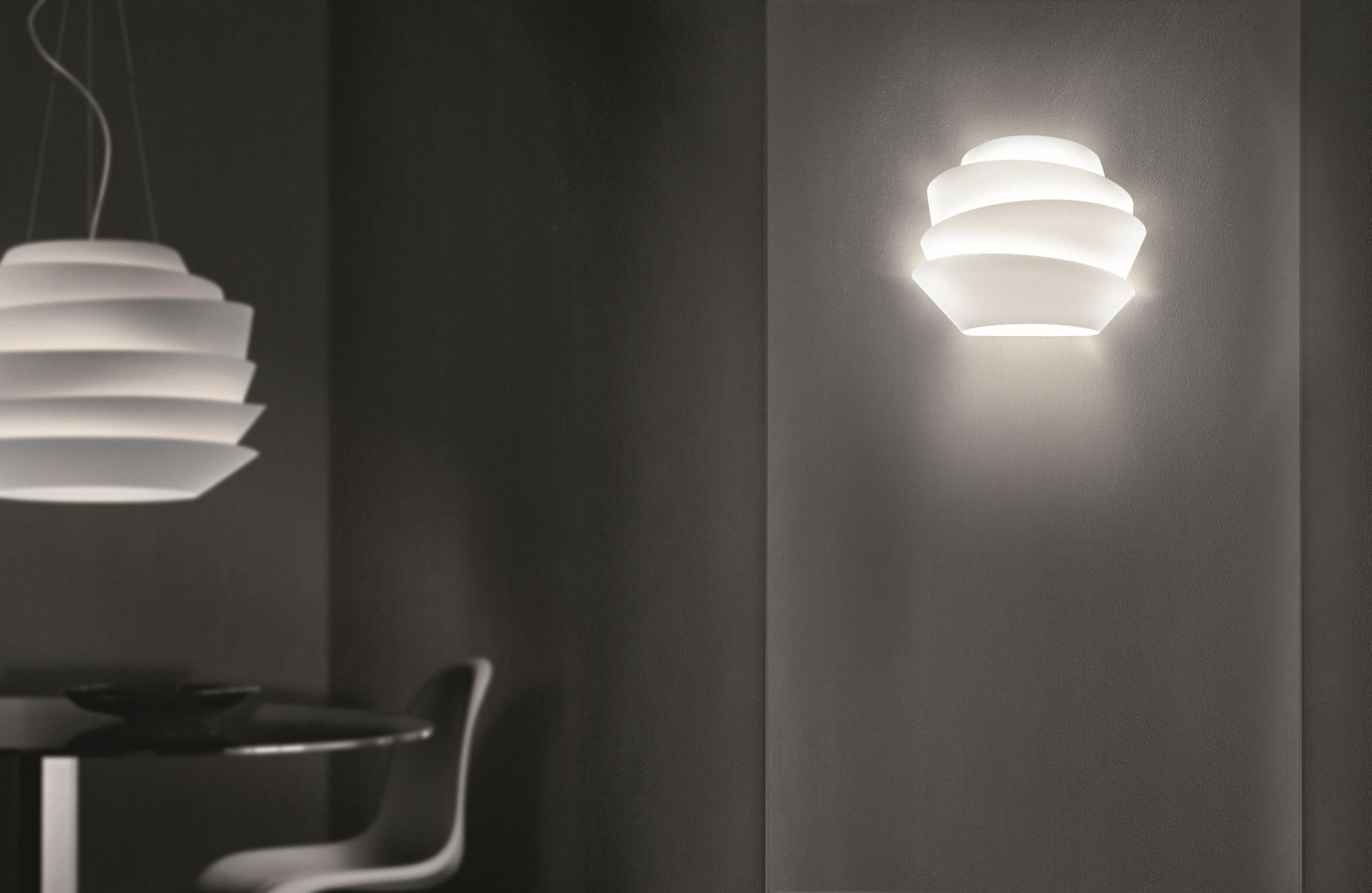 Weiße Le Soleil Wandleuchte von Foscarini an dunkler Wand, indirekte Beleuchtung für modernes Wohnambiente.