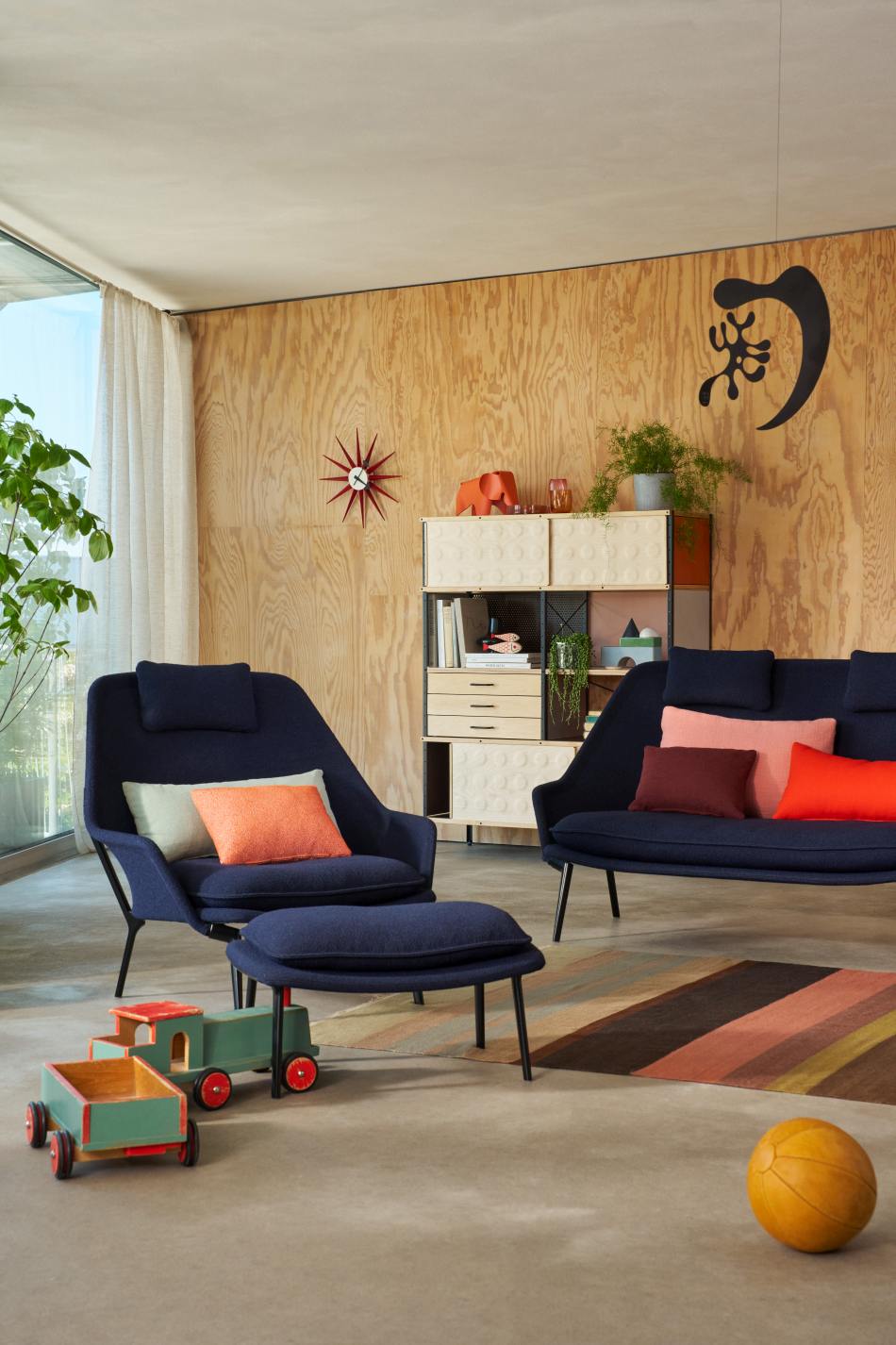 Blaues Vitra Slow Sofa und Sessel aus Stoff in modernem Wohnzimmer mit Holzvertäfelung.