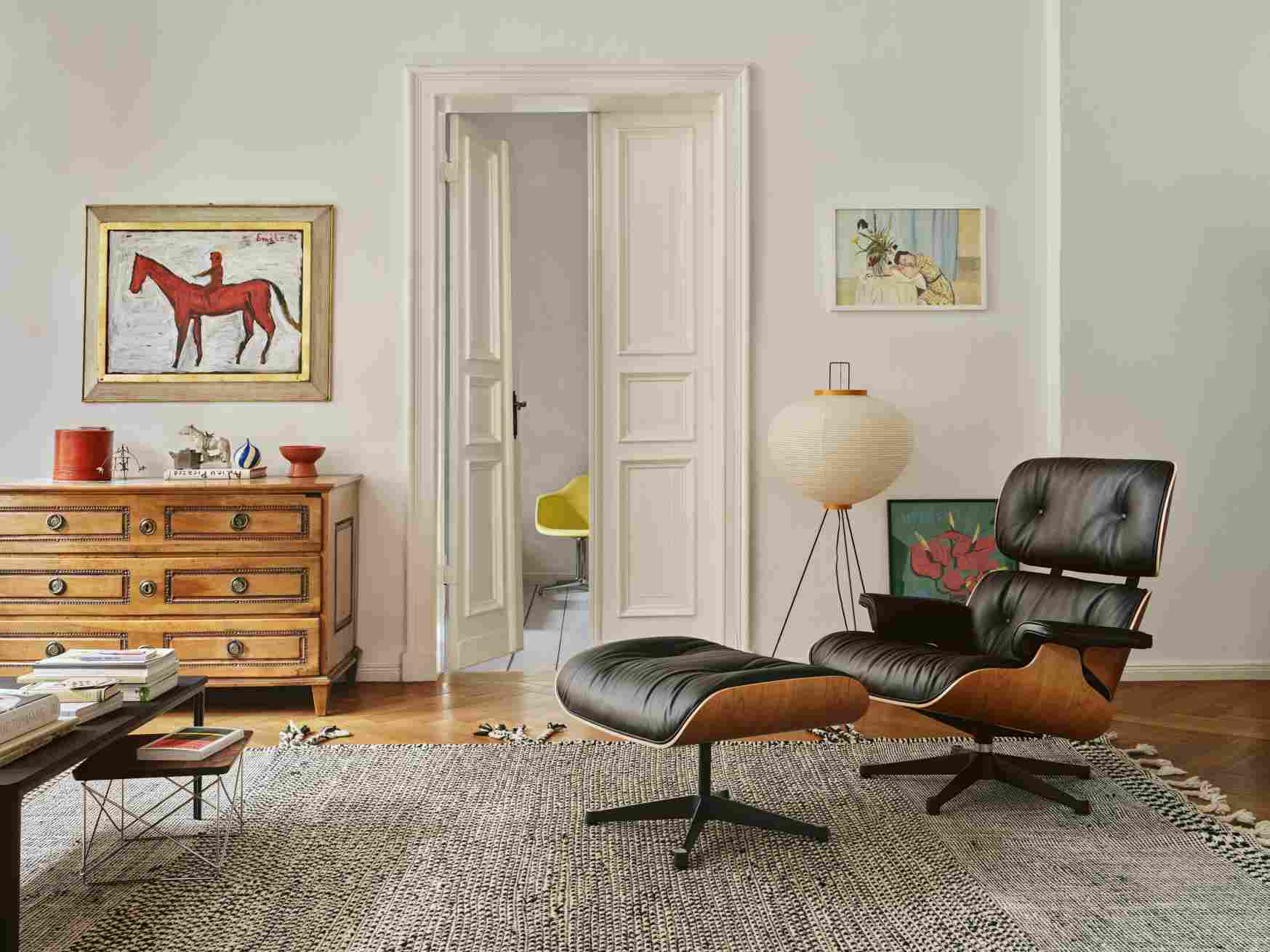 Eames Lounge Chair mit Ottoman in dunklem Leder und Holzfurnier in stilvollem Wohnzimmer.