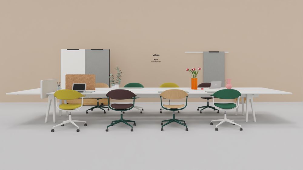 Vitra Mynt Bürodrehstühle aus Schichtholz in verschiedenen Farben an einem langen, weißen Konferenztisch.
