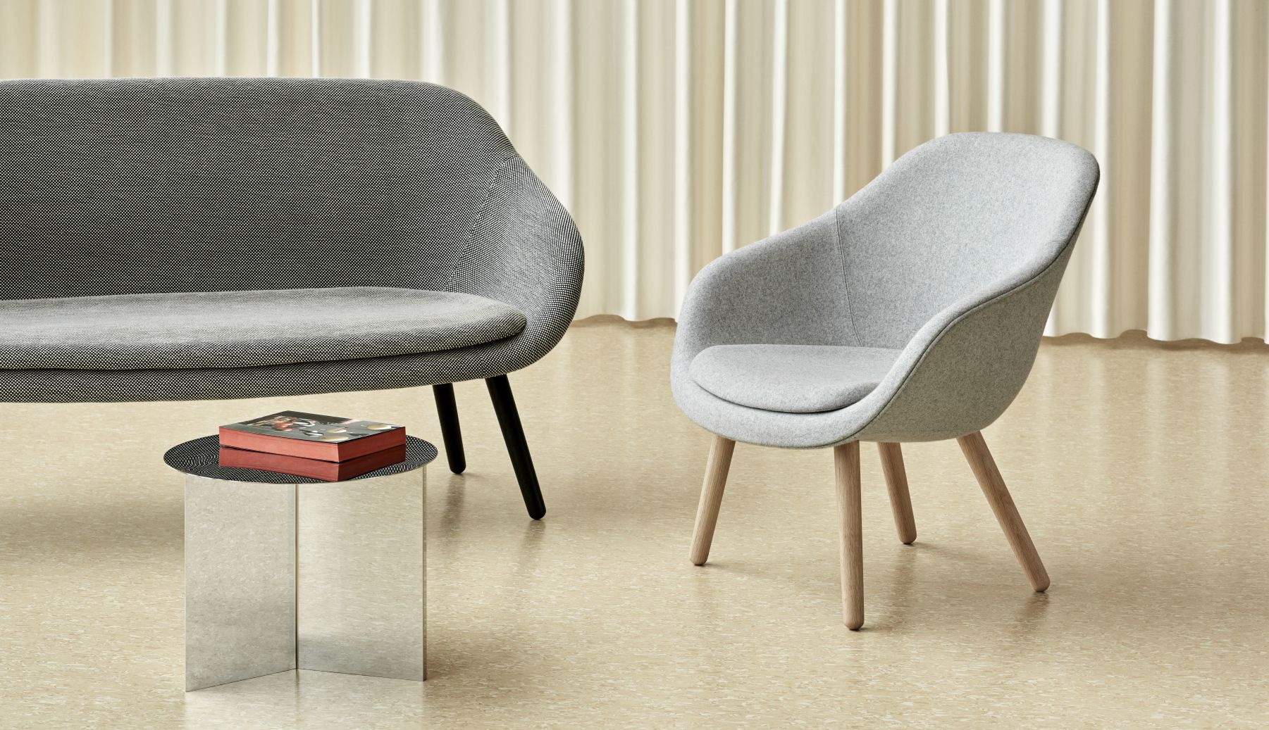 Nahaufnahme des Hay Slit Table Round Beistelltisch in poliertem Messing neben Sofa und Stuhl.
