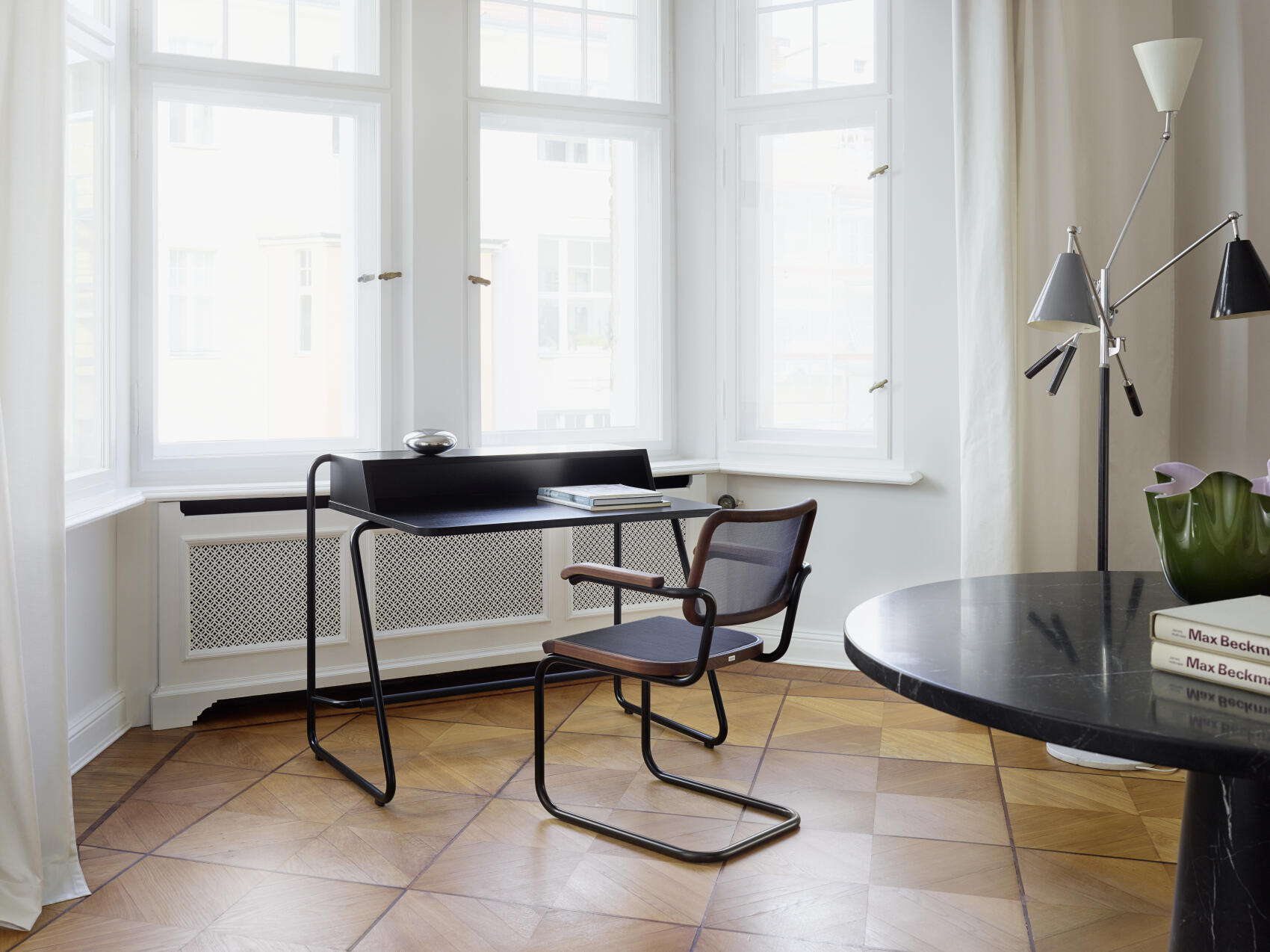 Schwarzer Schreibtisch mit Freischwinger Stuhl im hellen Raum. Modernes Design für Büro und Arbeitszimmer.