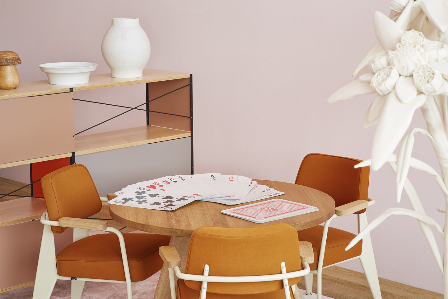 Vitra Fauteuil Direction Sessel in Orange um einen Holztisch mit Spielkarten, modernes Wohnambiente.