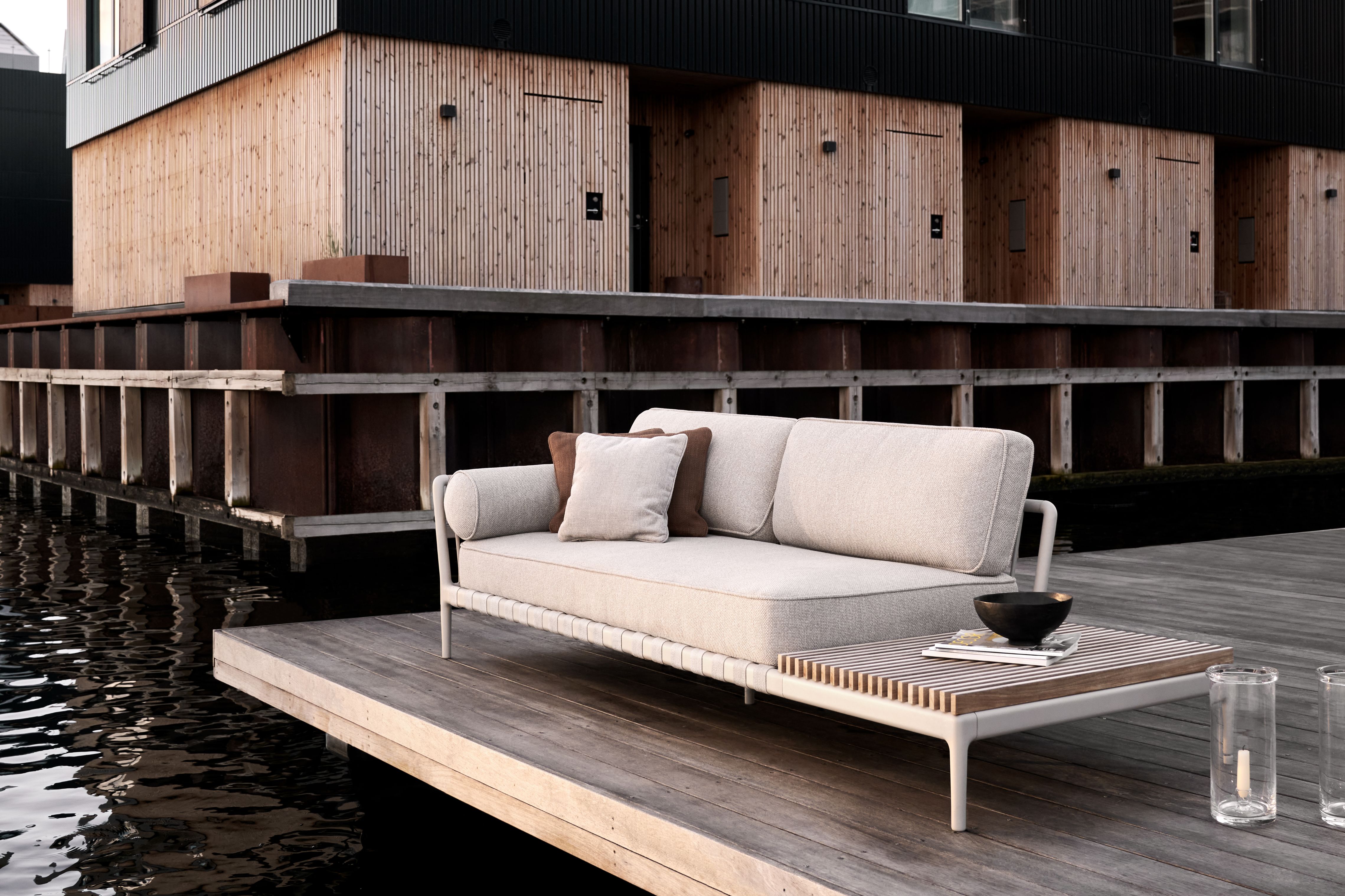 Vipp Open-Air Outdoor Sofa mit offenem Ende links auf Holzterrasse am Wasser.