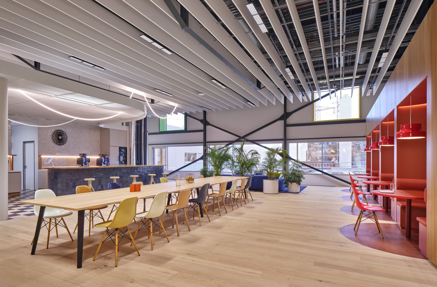 Helle Büroraum-Szene mit langer Tischreihe mit Eames DSW Stühlen und Sitzpolstern von Vitra.