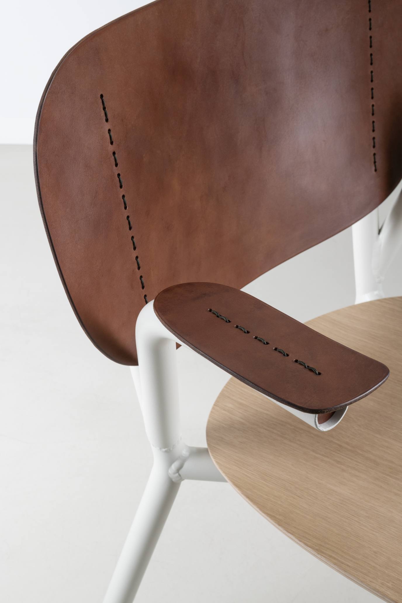 Detailaufnahme des Emil Rosi Armchair Stuhls: Leder, Holz, weißes Gestell, modernes Design für Wohnzimmer und Büro.