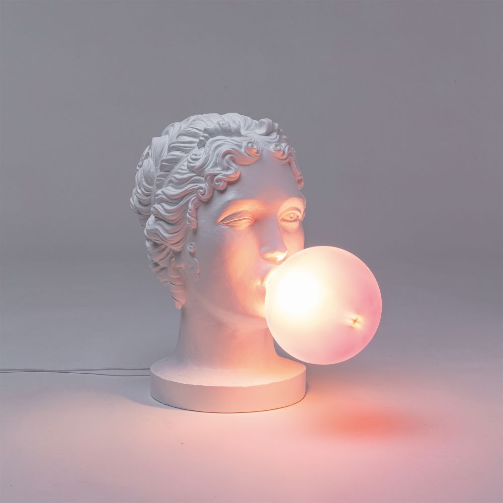 Grace Lamp von Seletti: Tischleuchte in Form einer weißen Frauenbüste mit leuchtender Kugel.