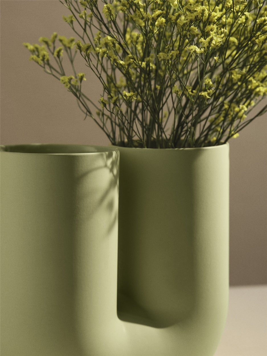 Nahaufnahme der grünen Kink Vase von Muuto mit zarten gelben Blüten. Dekorative Design-Vase für Blumen.