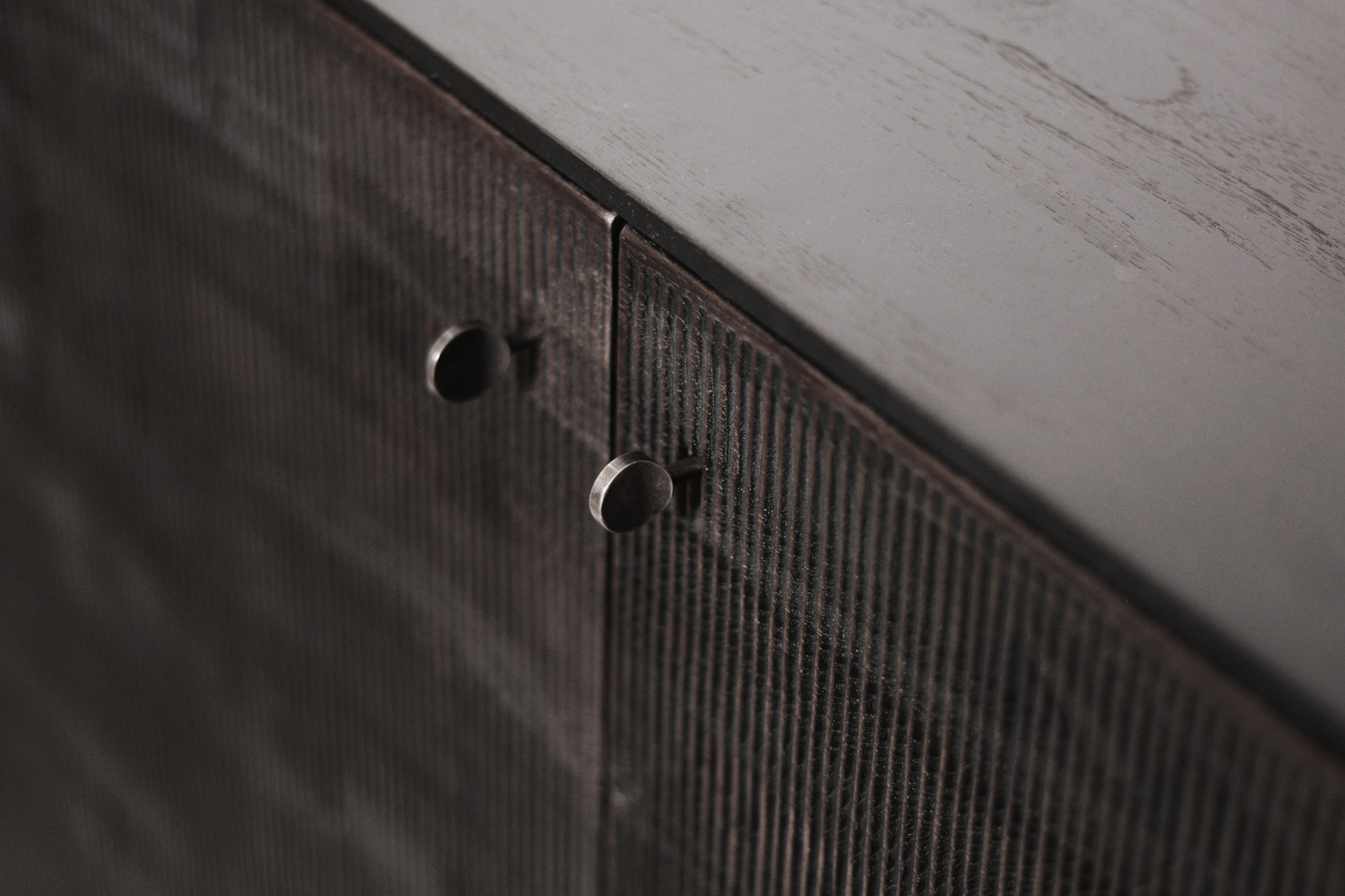 Detailaufnahme des Ethnicraft Teak Grooves Schrankes mit gerillten Türen und runden Metallgriffen.