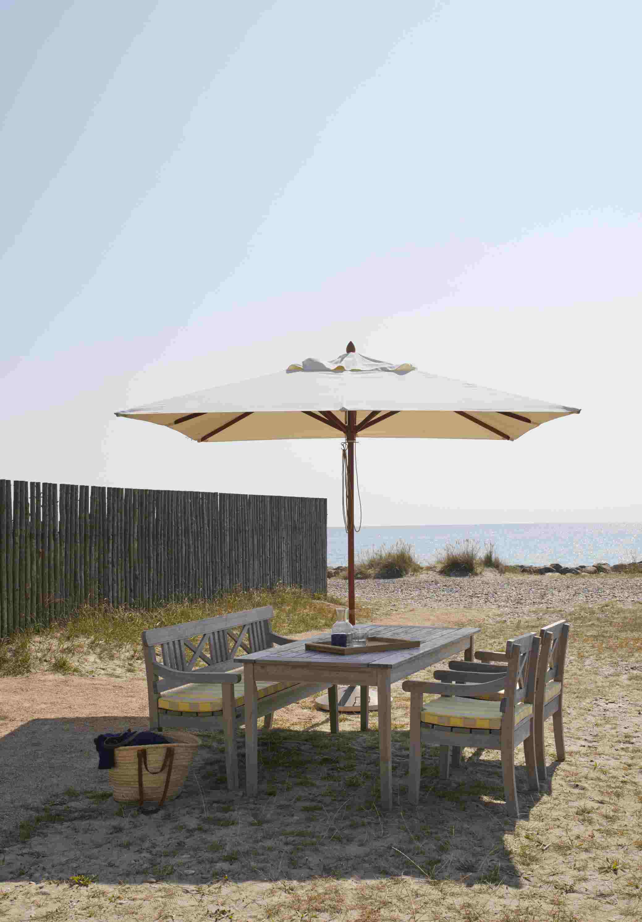 Drachmann Stuhl mit hellem Apricot Sitzkissen und dunkelgrünen Streifen im Outdoor-Bereich.