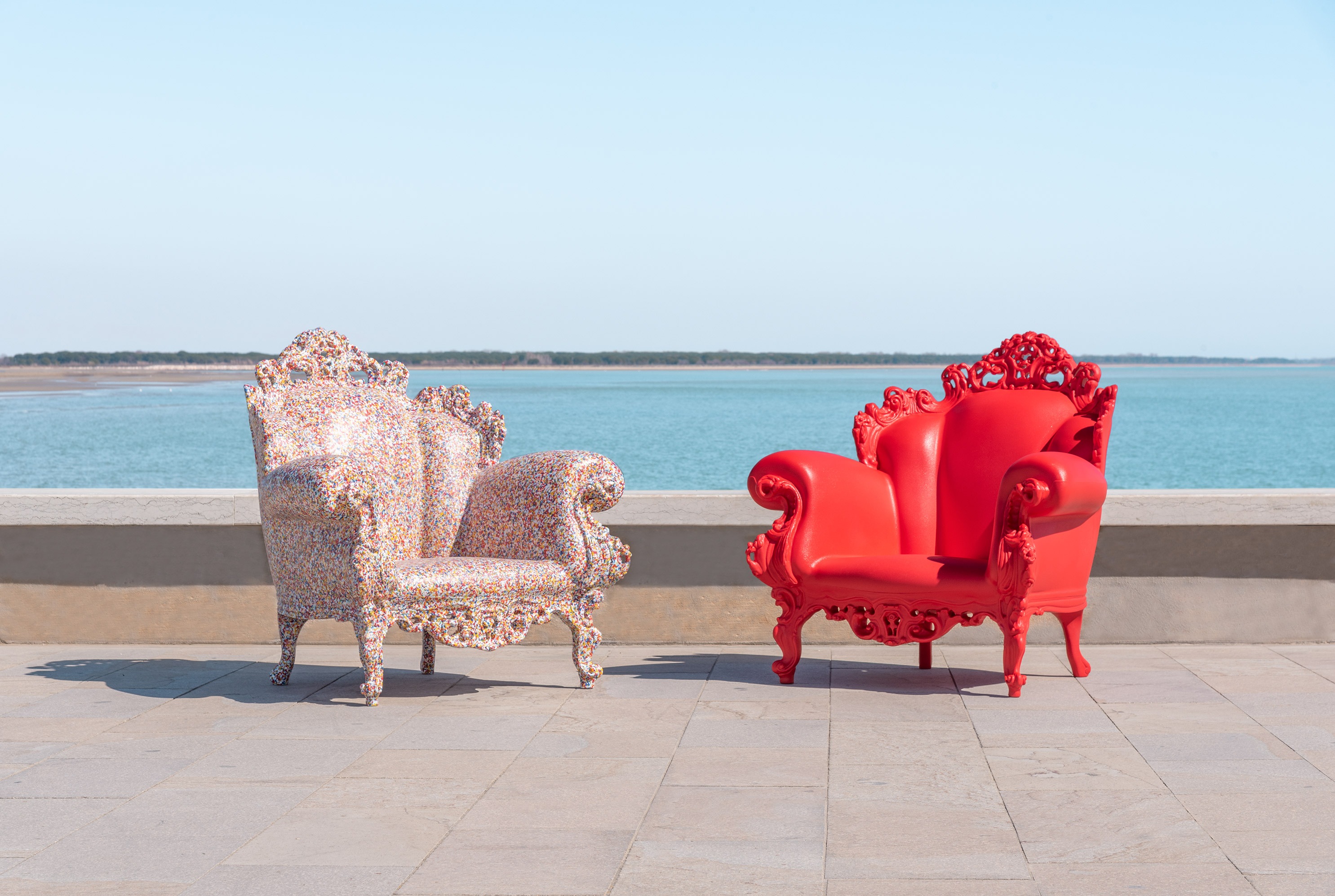 Zwei Magis Proust Sessel Outdoor, einer rot, einer bunt, vor Meer und blauem Himmel.