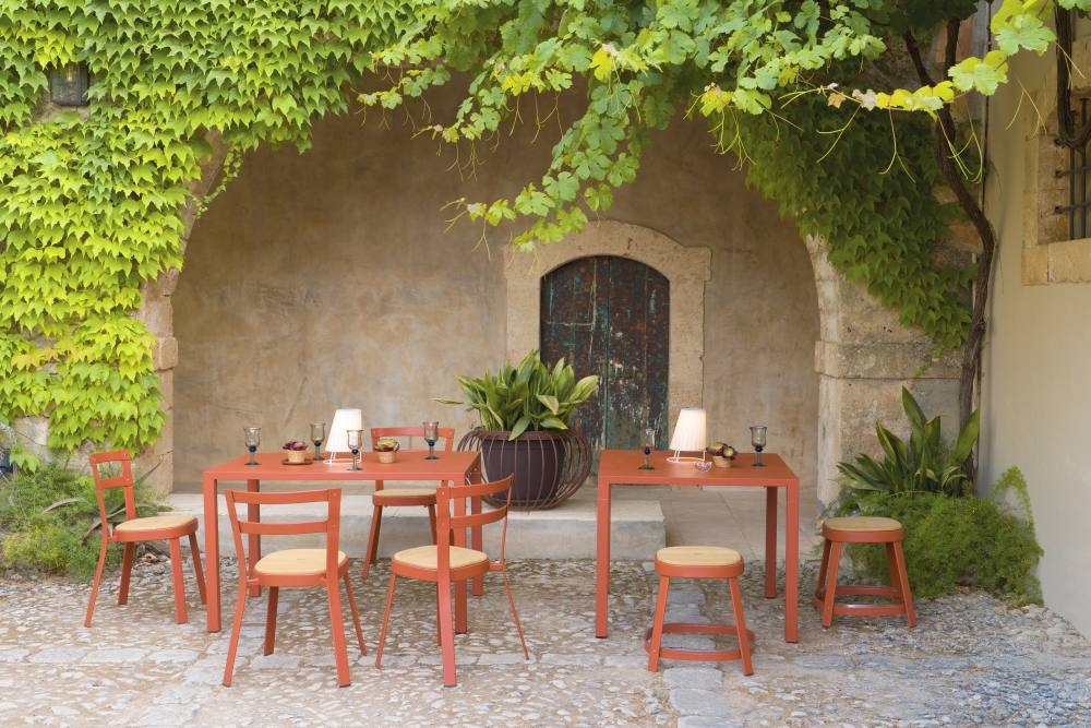 Emu Thor Chair Outdoor Sitzgruppe mit Tisch und Stühlen in Terrakotta vor Steinmauer.