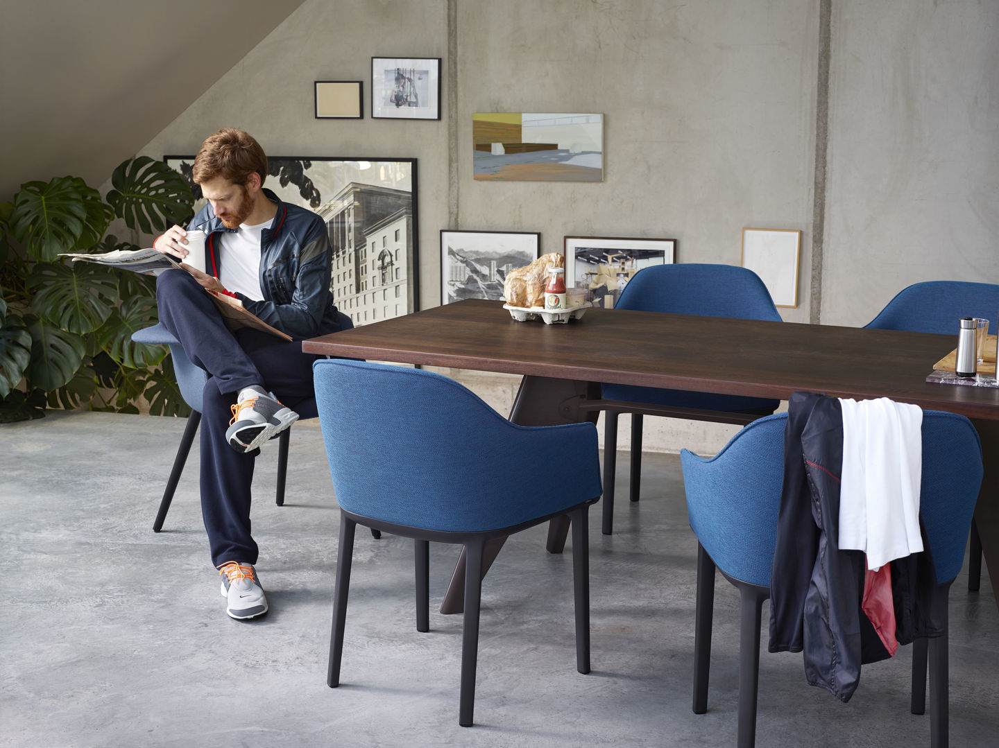 Blauer Organic Conference Stuhl von Vitra an einem Esstisch mit lesendem Mann.