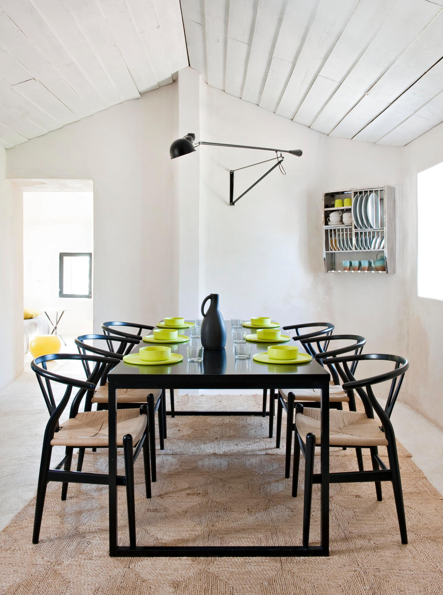 Esszimmer mit schwarzem Tisch, Stühlen und Flos 265 Wandleuchte für indirektes Licht.