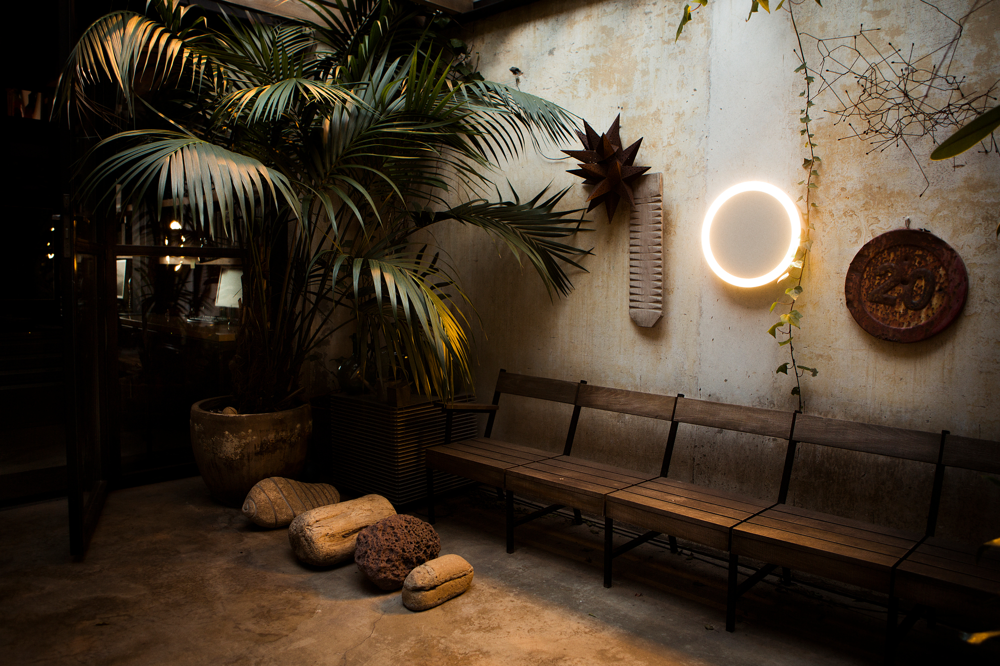 Amigo Outdoor LED Deckenleuchte von Santa & Cole beleuchtet eine rustikale Außenterrasse mit Holzbänken.