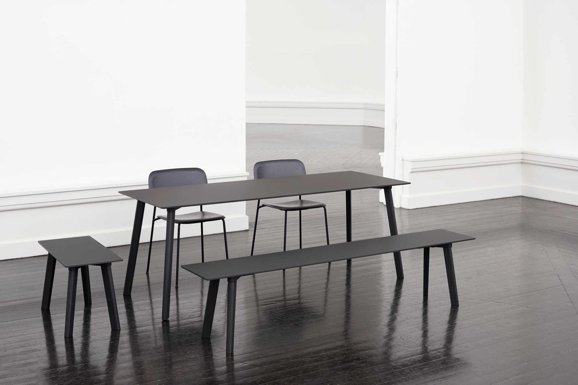 Schwarzer Hay Soft Edge Stuhl mit Tisch und Bank in minimalistischem Interieur.