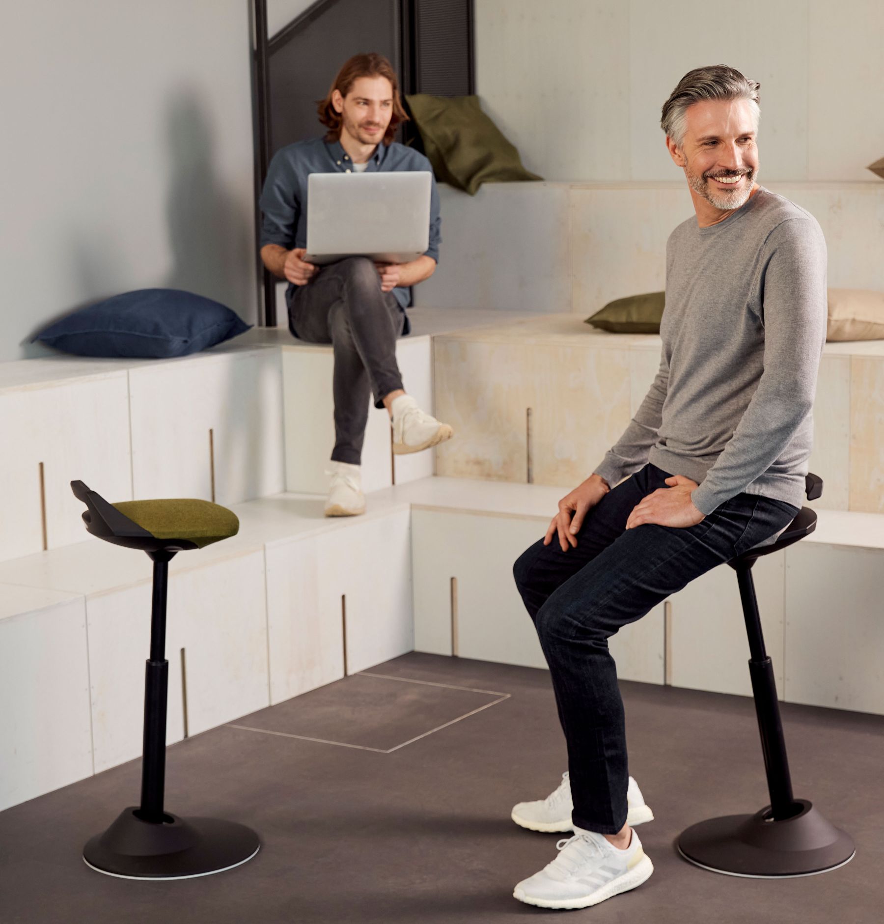 Muvman Stehhocker mit Mann im Büro, ergonomischer Sitzhocker für dynamisches Sitzen.