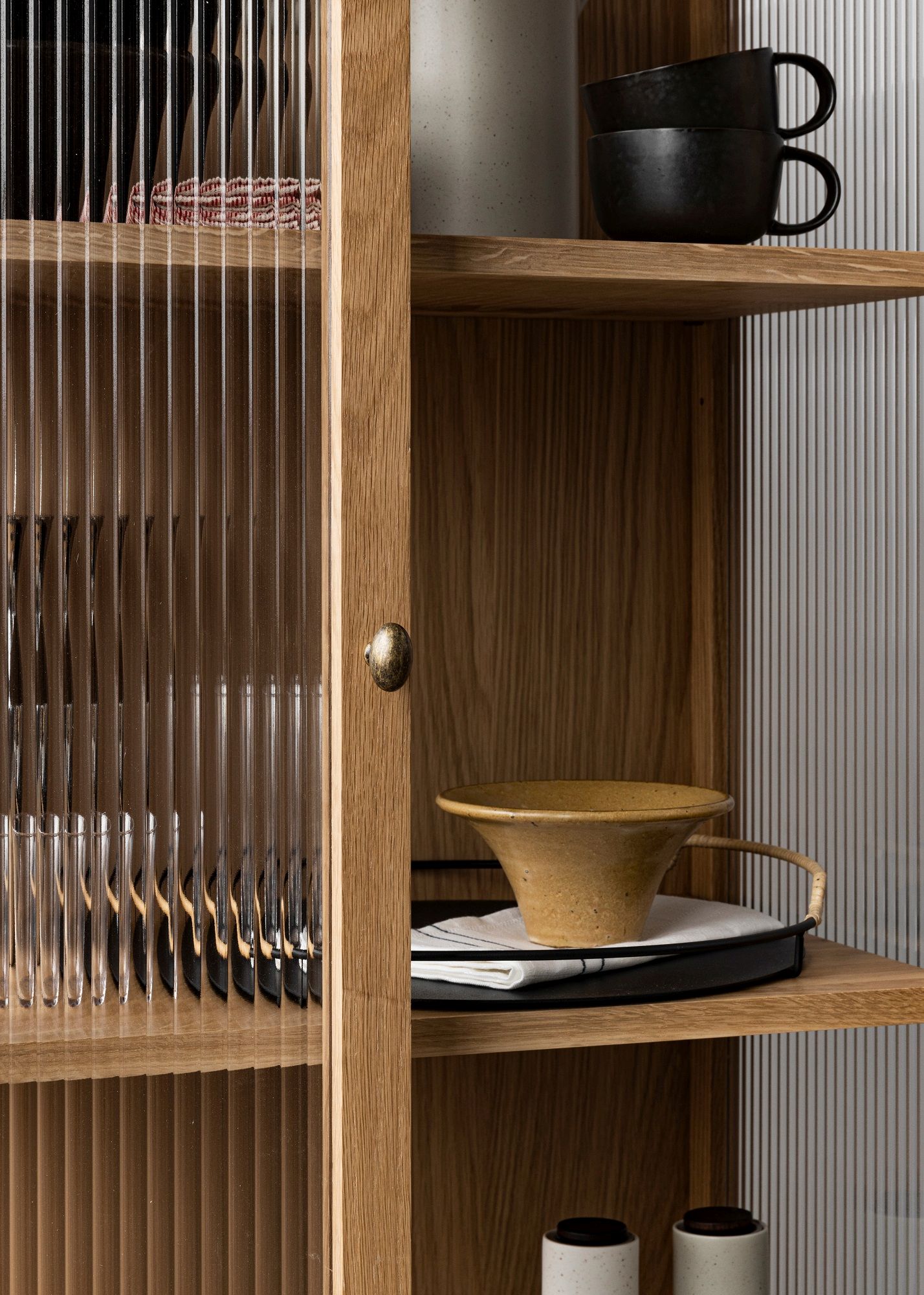 Detailaufnahme des Curiosity Cabinet Schranks von Audo Copenhagen mit Glasfront und Eichenholz Regalböden.