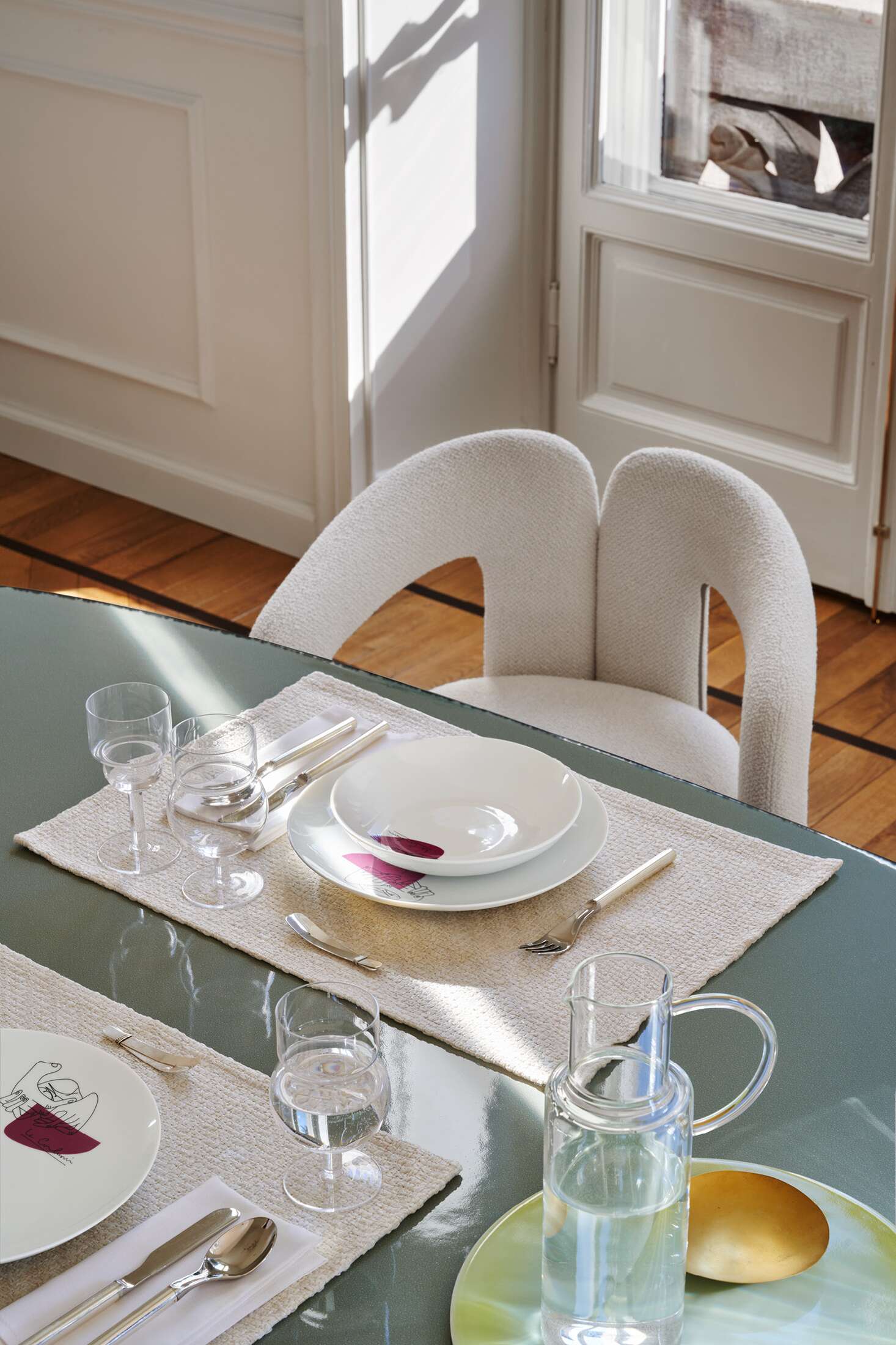 Nahaufnahme des Cassina 562 Dudet Sessels am Esstisch mit Geschirr und Gläsern, modernes Möbeldesign.