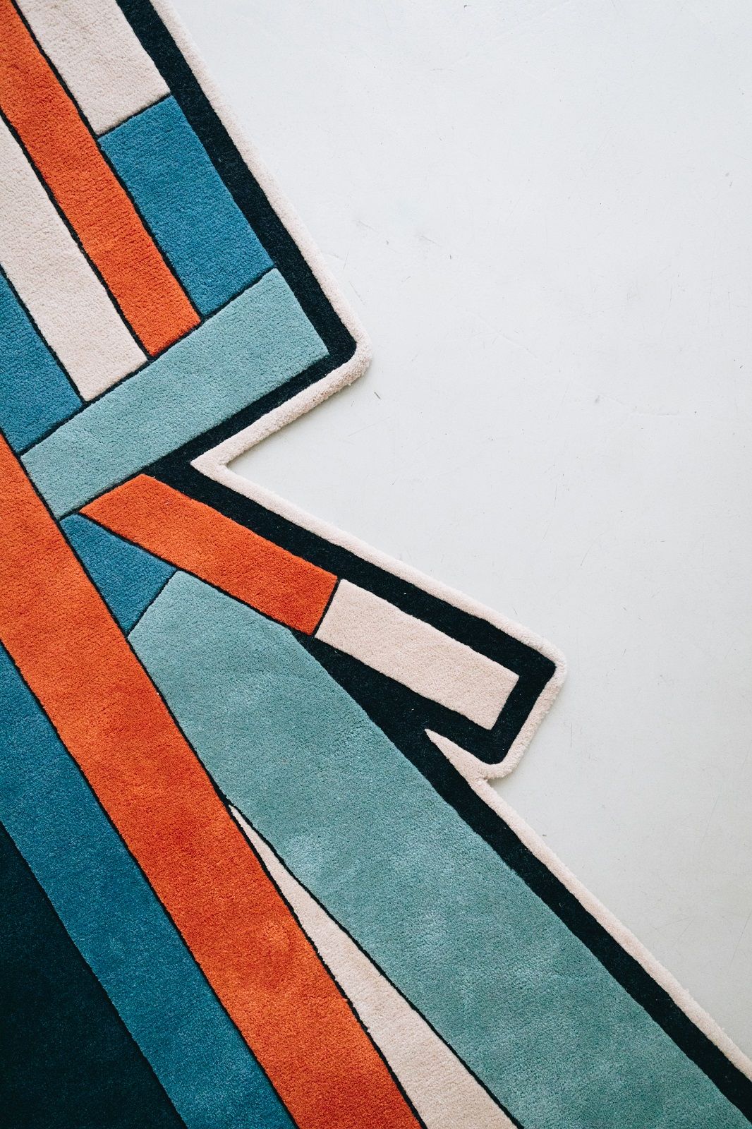 Detailaufnahme des Inès Carpet Teppich Hart mit geometrischem Muster in Orange, Blau und Beige.