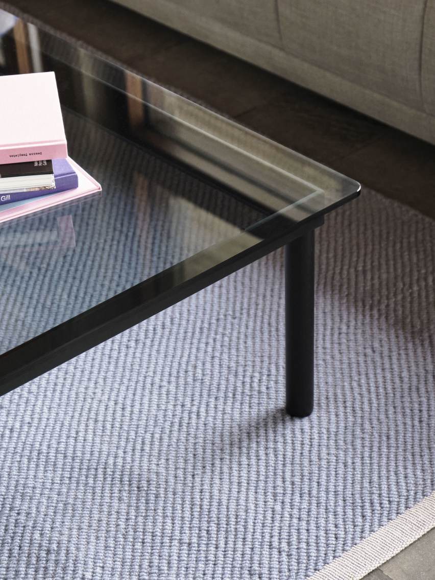 Detailaufnahme: Kofi Couchtisch mit Klarglas geriffelt und schwarzem Rahmen auf einem Teppich.