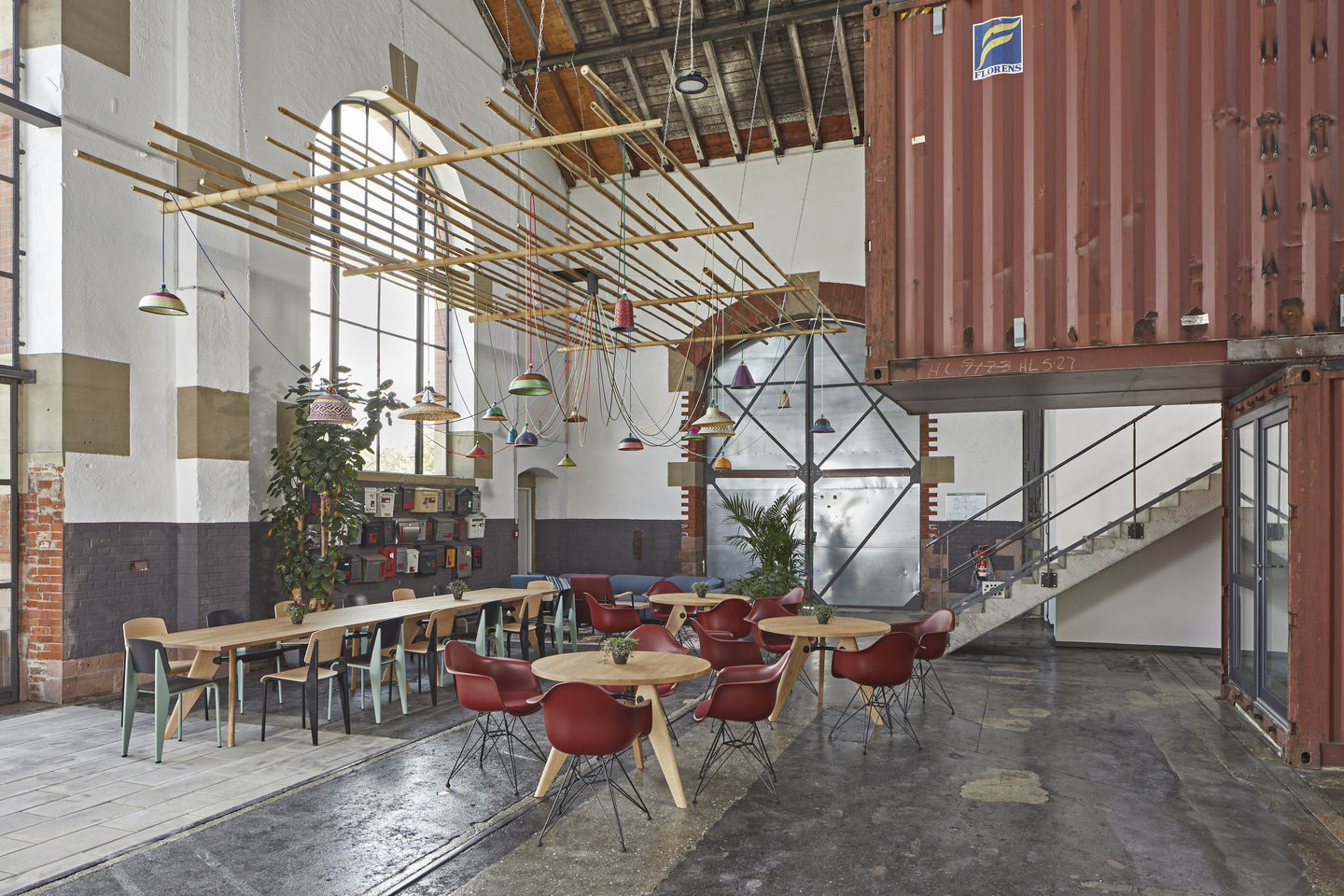 Innenraum mit Eames Plastic Arm Chairs DAR Stühlen von Vitra und Holztischen.