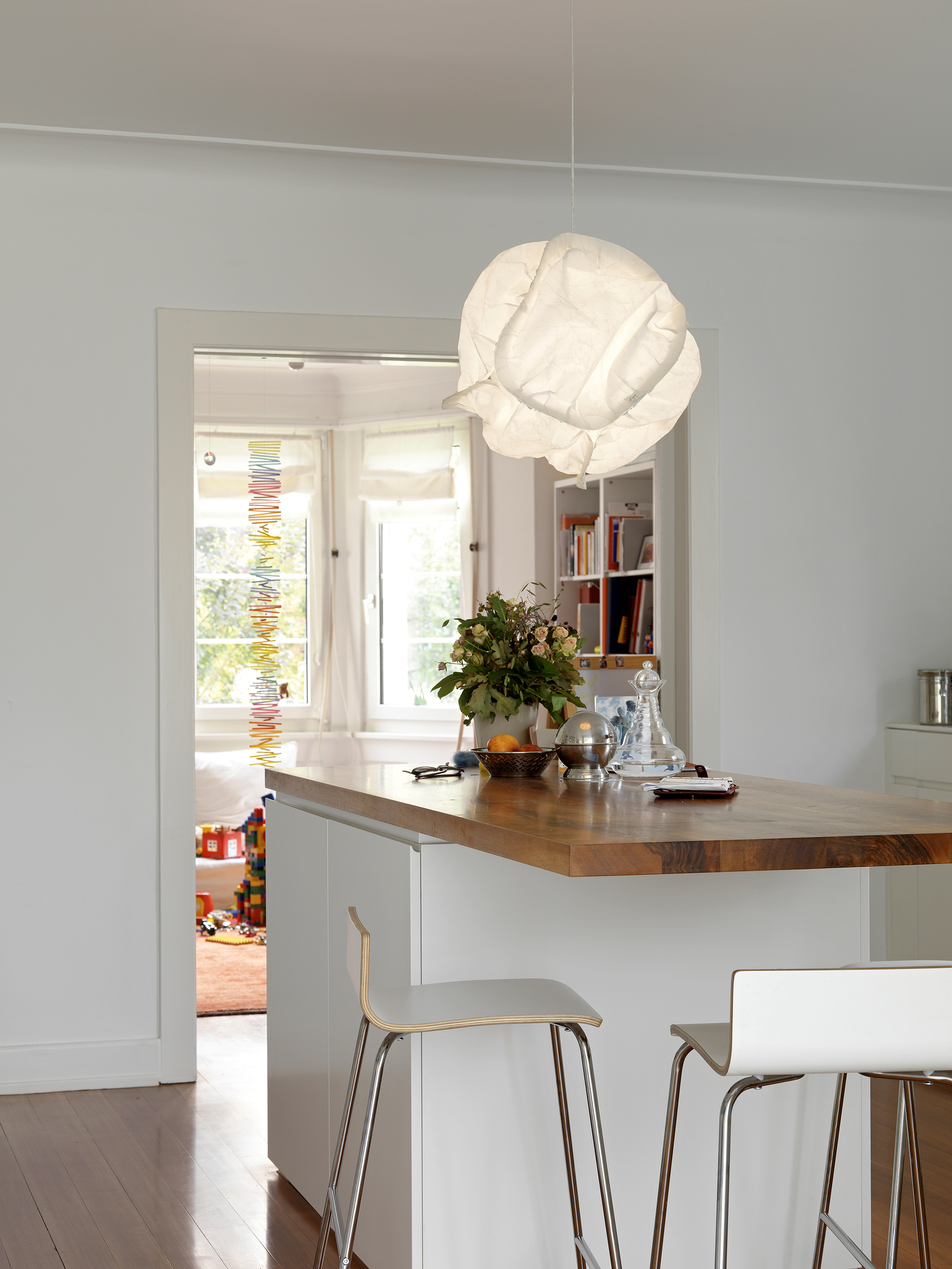 Belux Cloud LED Pendelleuchte über einer modernen Küchentheke mit Holzarbeitsplatte und weißen Barhockern.