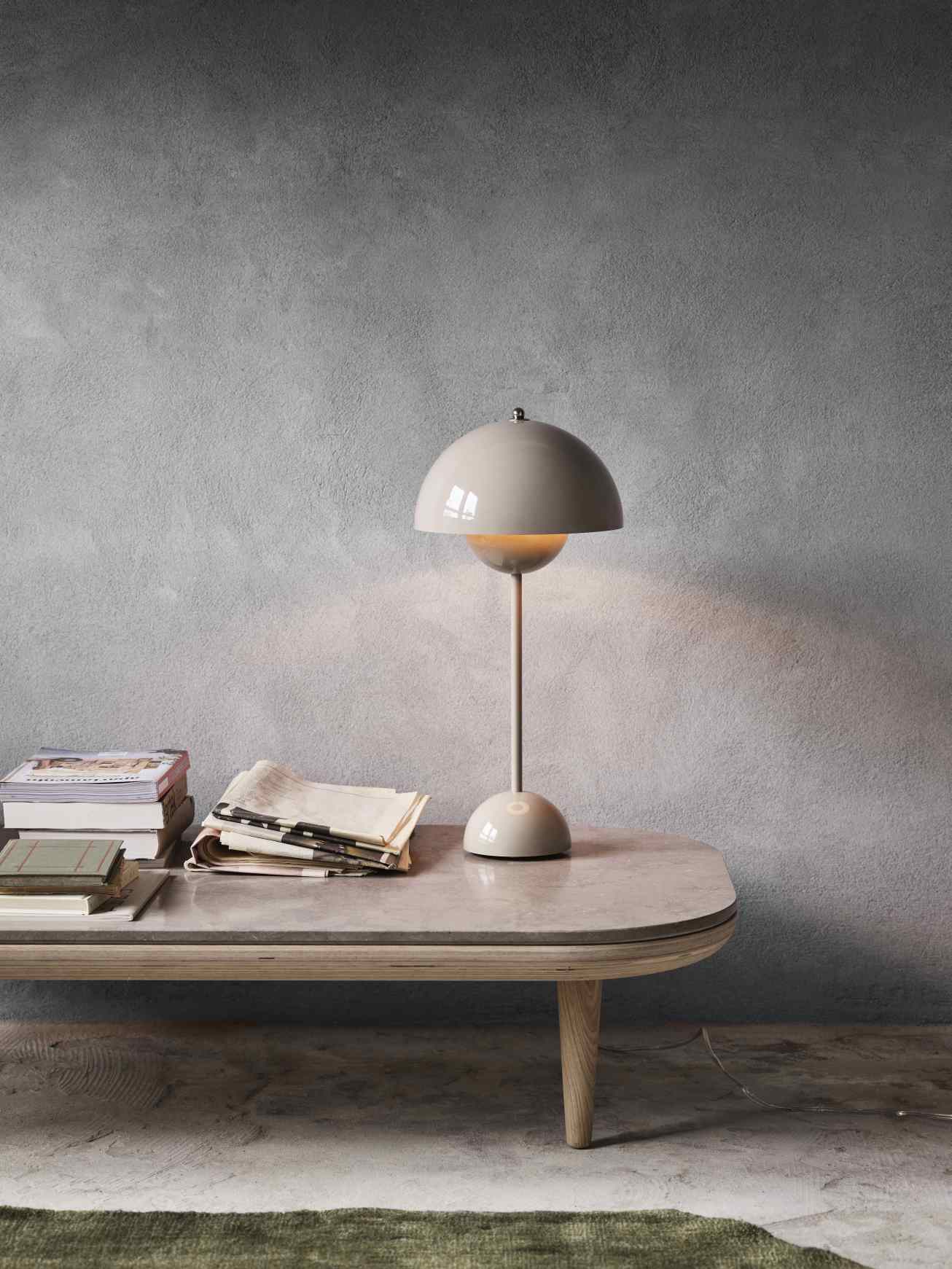 AndTradition Fly Table Couchtisch mit grauer Tischleuchte, Büchern und Zeitungen auf einer Marmorplatte.