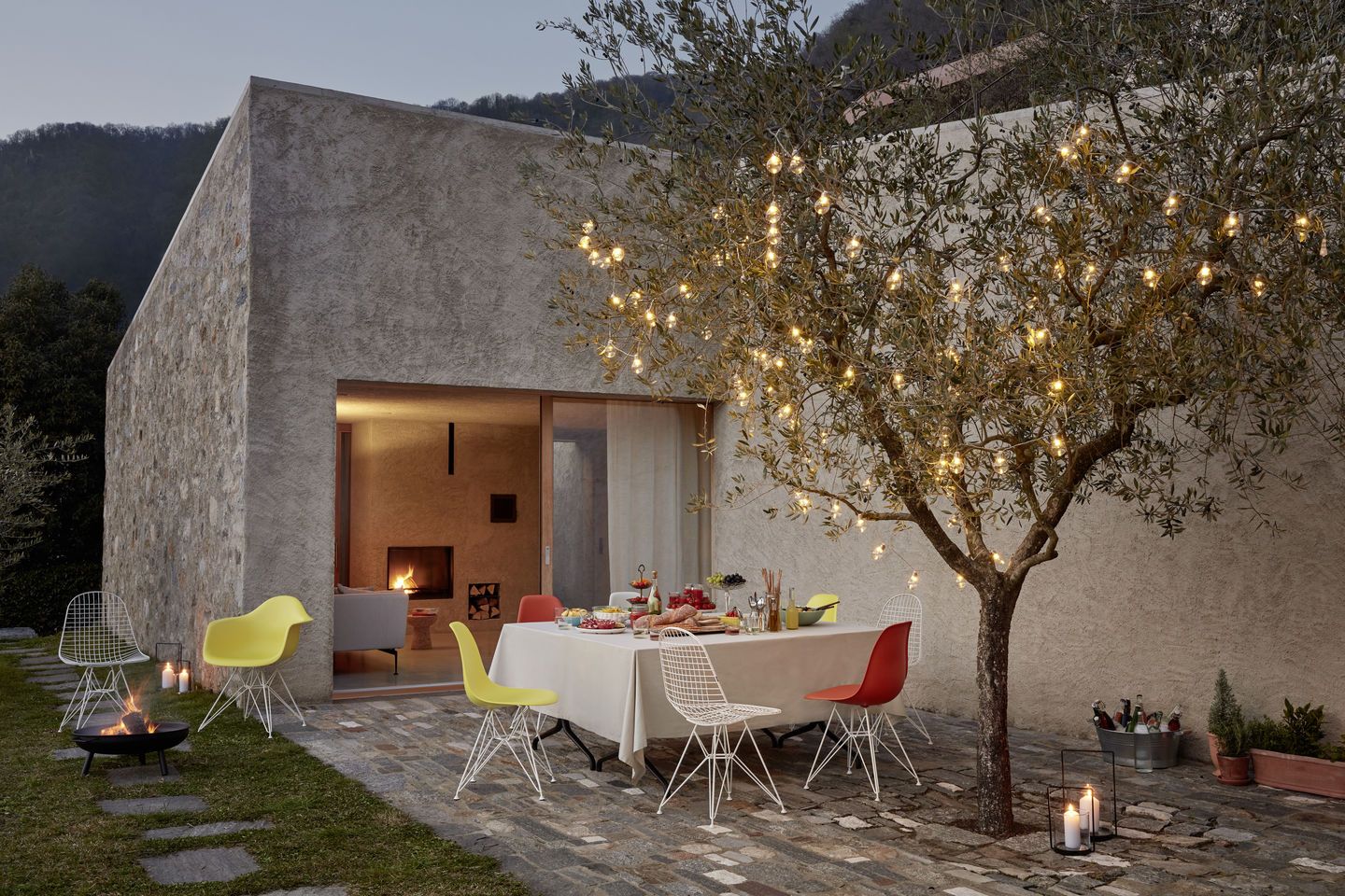 Eames Fiberglass Chair DSR Stuhl von Vitra mit Sitzpolster in Gartenambiente mit Esstisch und Beleuchtung.