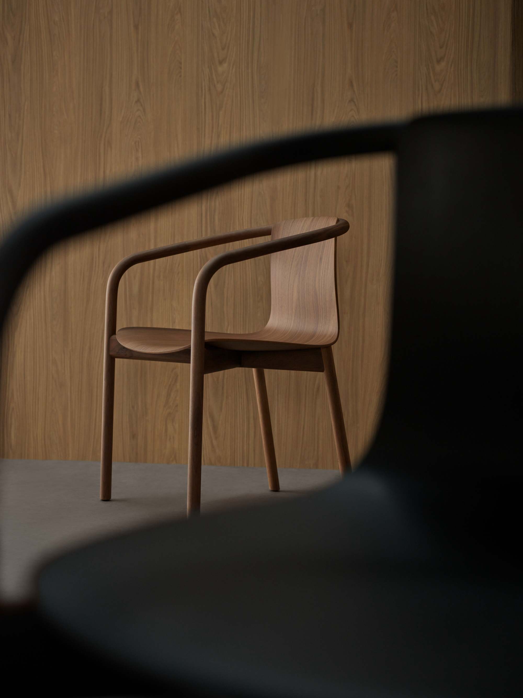 Osuu Chair von Walter Knoll: Holzstuhl mit Armlehne vor einer Holzwand.