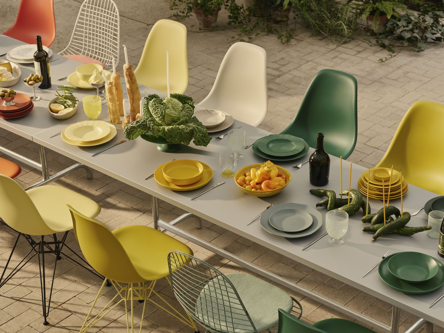 Esstisch im Freien mit bunten Eames DSR Stühlen von Vitra und sommerlicher Tischdekoration.