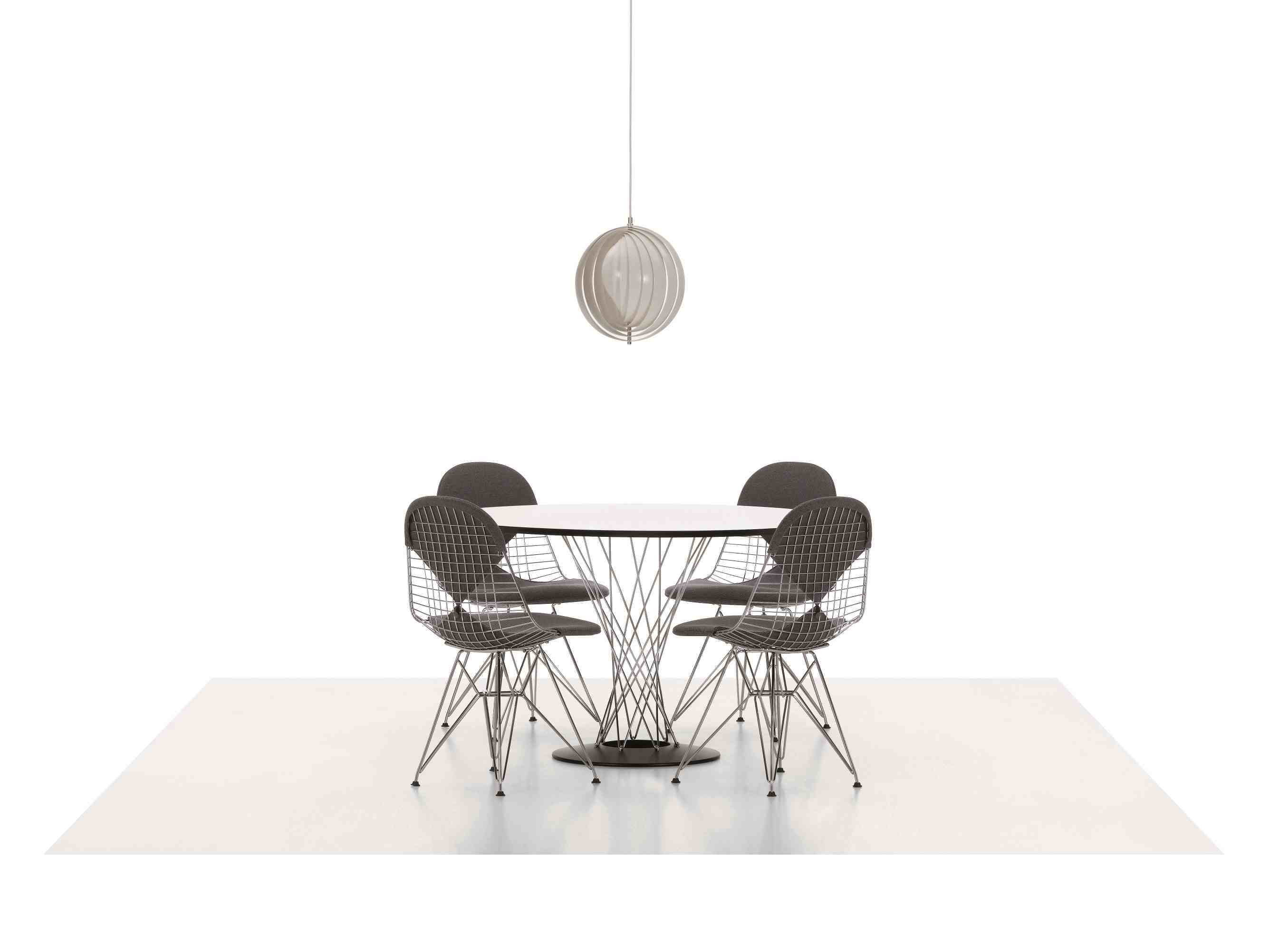 Vitra Noguchi Dining Table mit vier Wire Chairs und einer Hängelampe auf hellem Teppich.