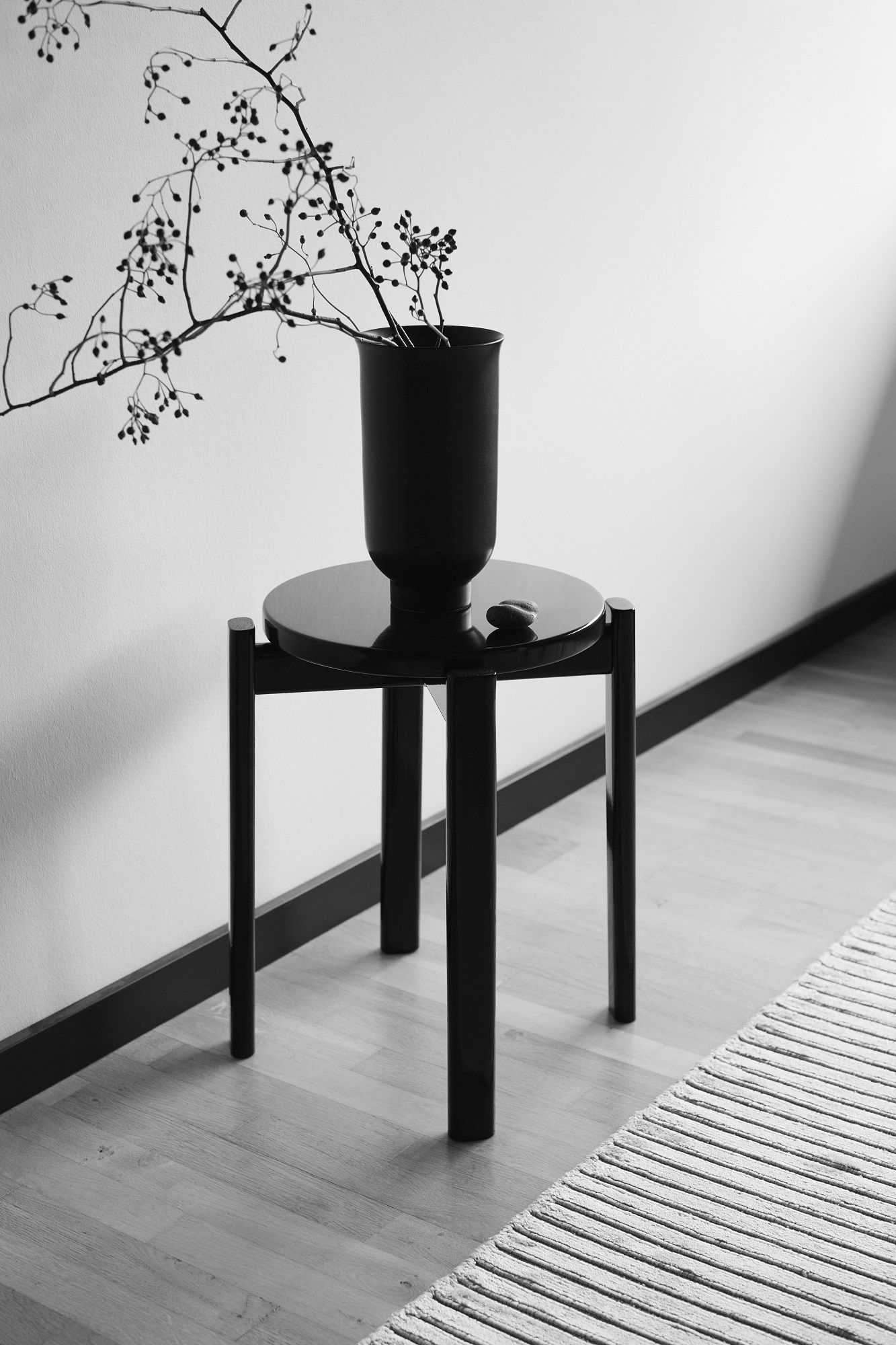 Schwarzer Passage Stool Hocker von Audo Copenhagen mit Vase und Zweigen im minimalistischen Interieur.