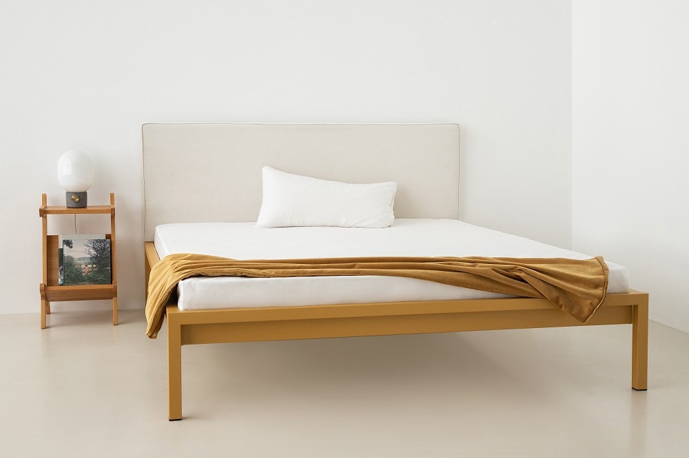 Pure Bett mit sandgoldenem Stahlrahmen und Polsterkopfteil, modernes Schlafzimmerdesign.
